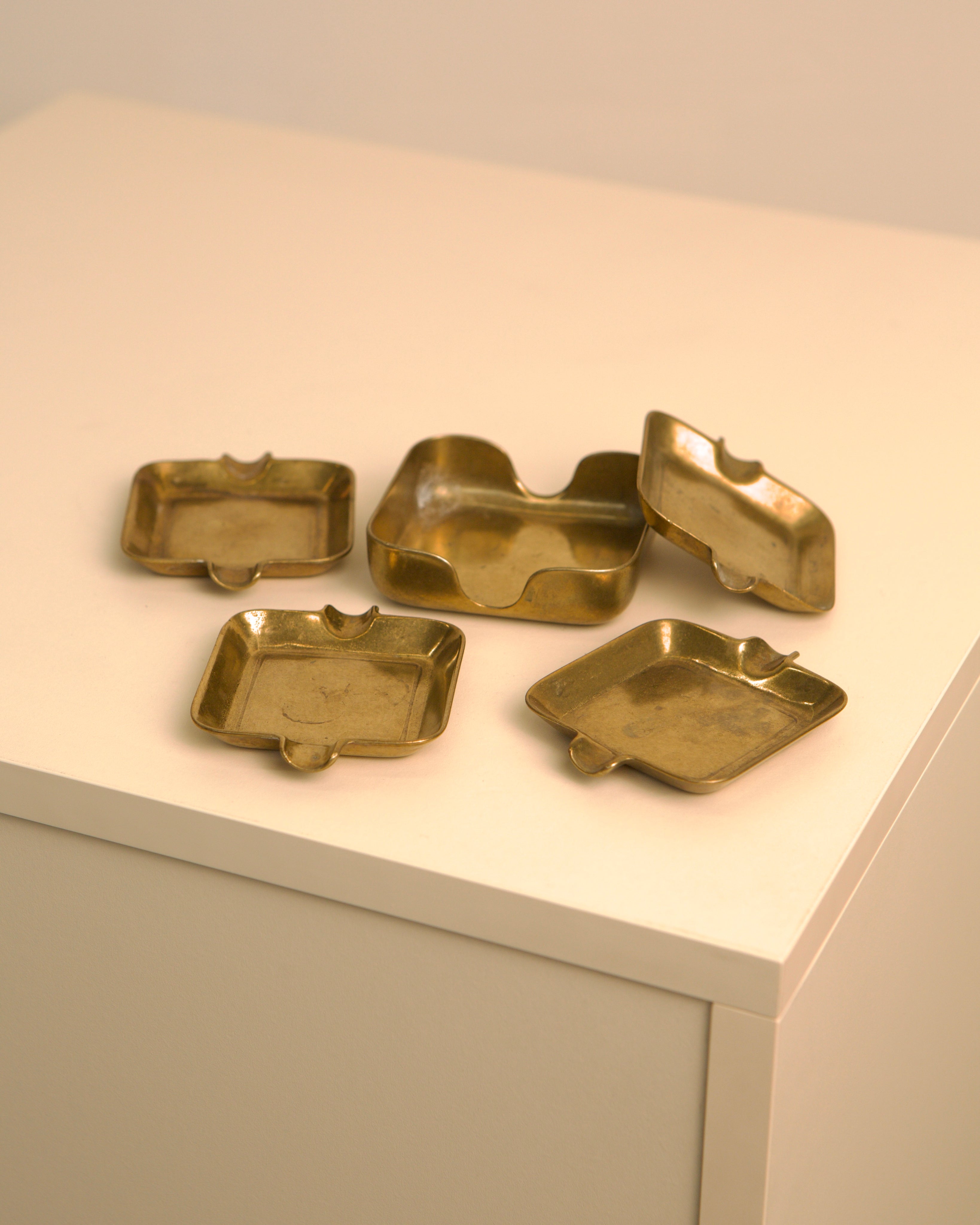 Five vintage Italian brass ashtrays arranged on white surface