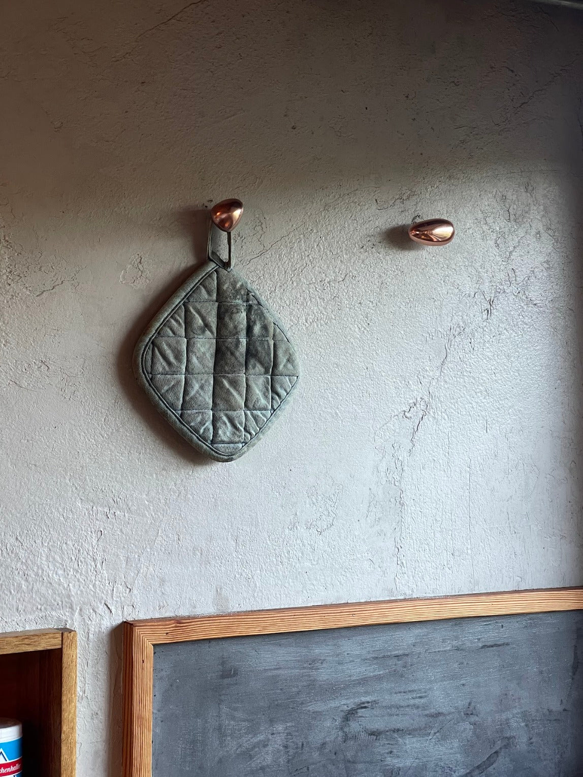 MOMI Cabinet Knob/Wall Hook Long Mini — mounted on textured wall with pot holder