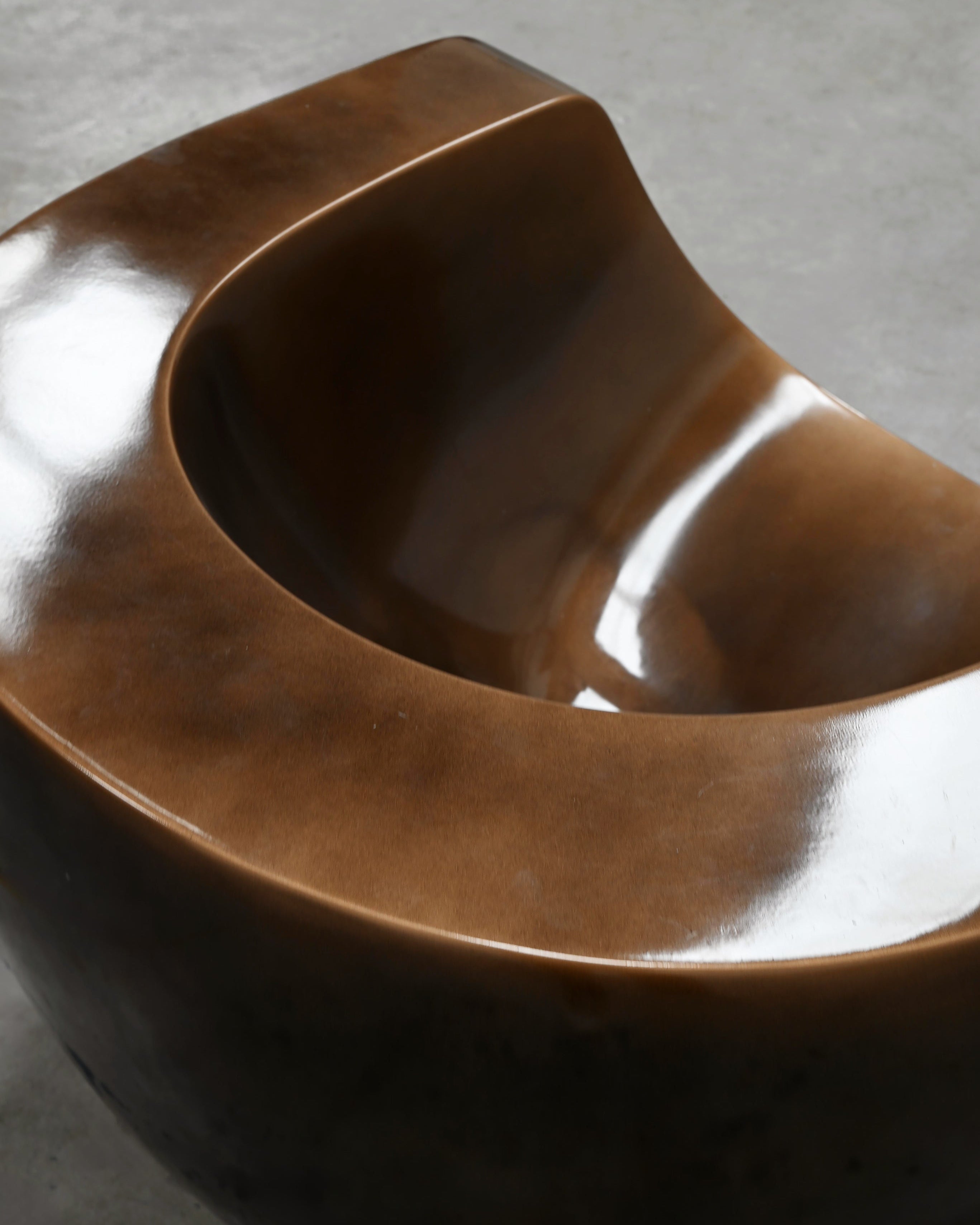 Close-up detail of sculptural brown fiberglass Moon chair curves