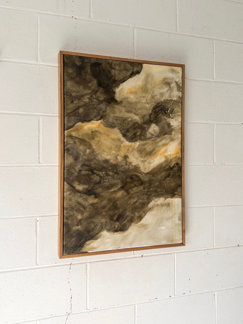 “Recess Of Dreams,” an original mixed media on canvas by Natasha France, features swirling brown, tan, and creamy white tones. Displayed slightly angled on a white-painted brick wall, the piece evokes an earthy, organic feel.