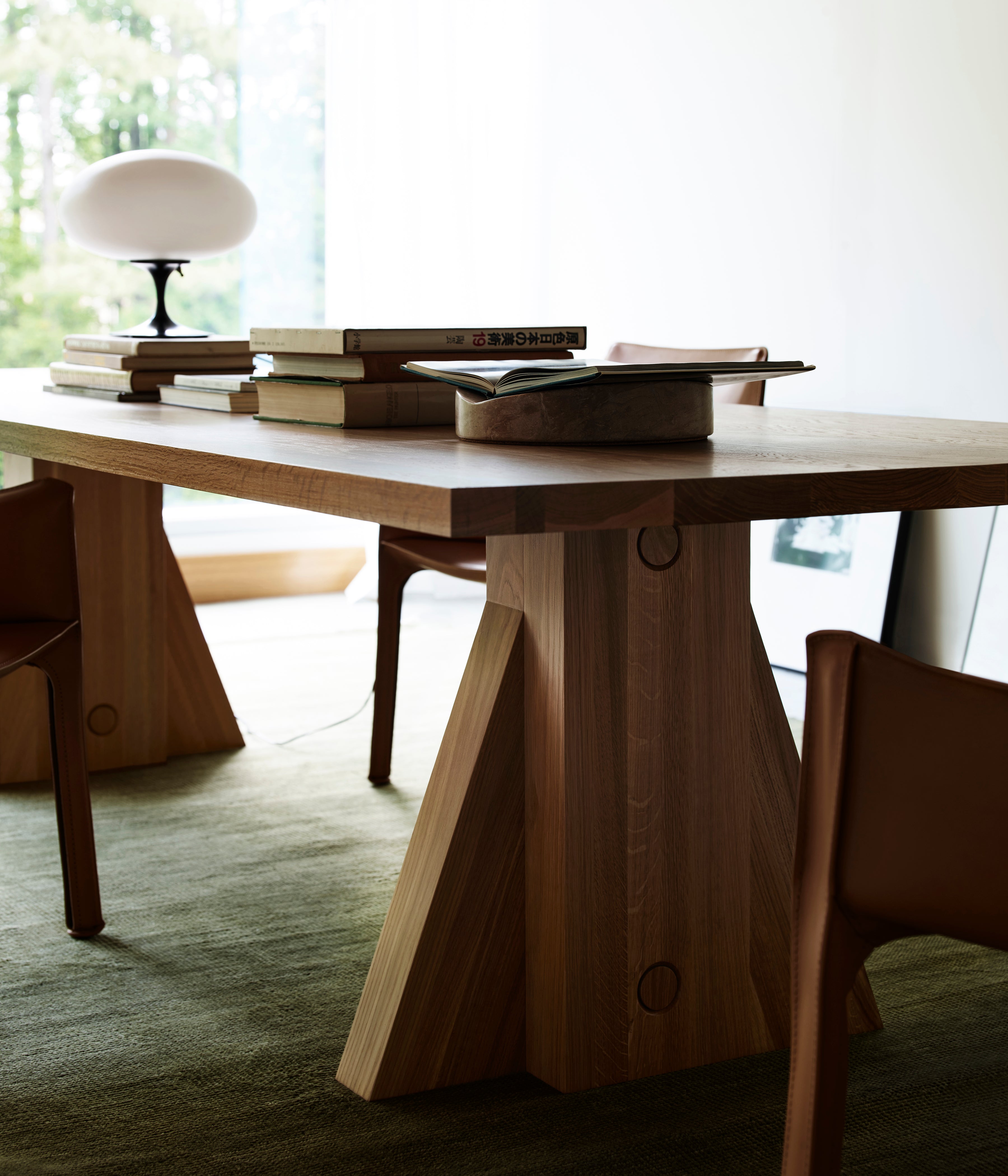 Elmyr Dining Table — side angle showing wooden base and books