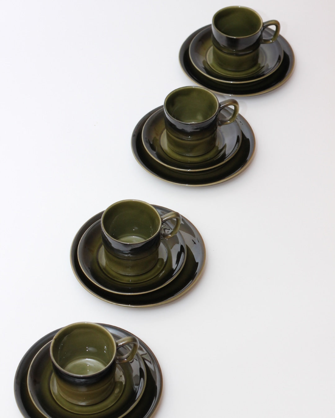 Set of Four Ceramic Cups — top view of green and black cups on plates