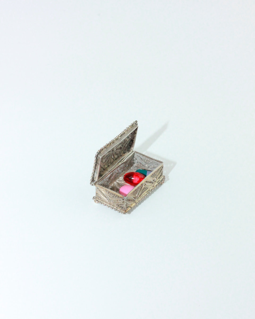 Silver Pillbox — side angle showing silver finish and colorful pills inside