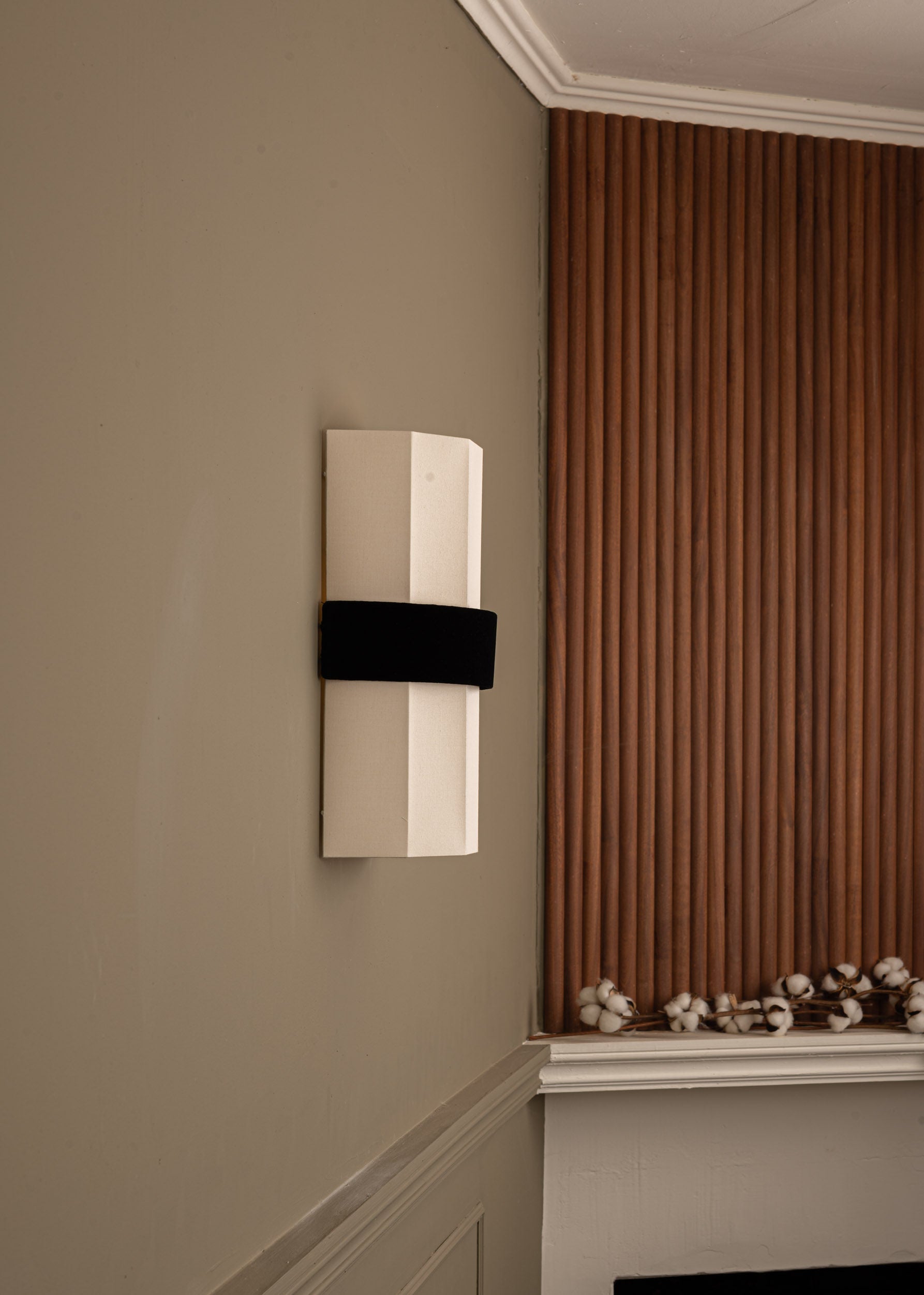 Okla black velvet wall light mounted on beige wall beside fireplace
