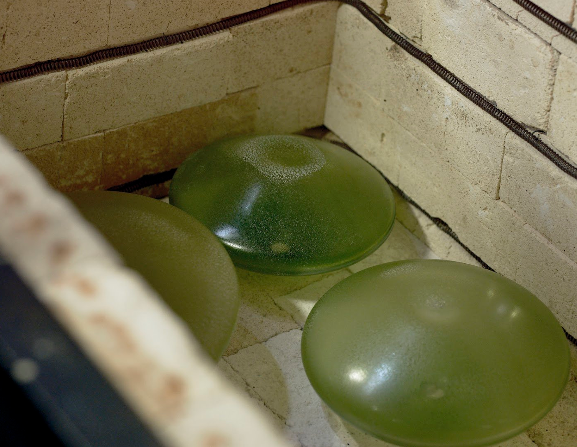 The Scavo Lamp — side view of green glass shades in kiln