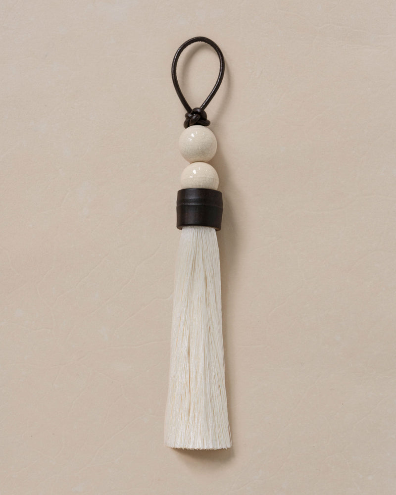 Elegant white tassel ornament with ceramic beads and leather cord