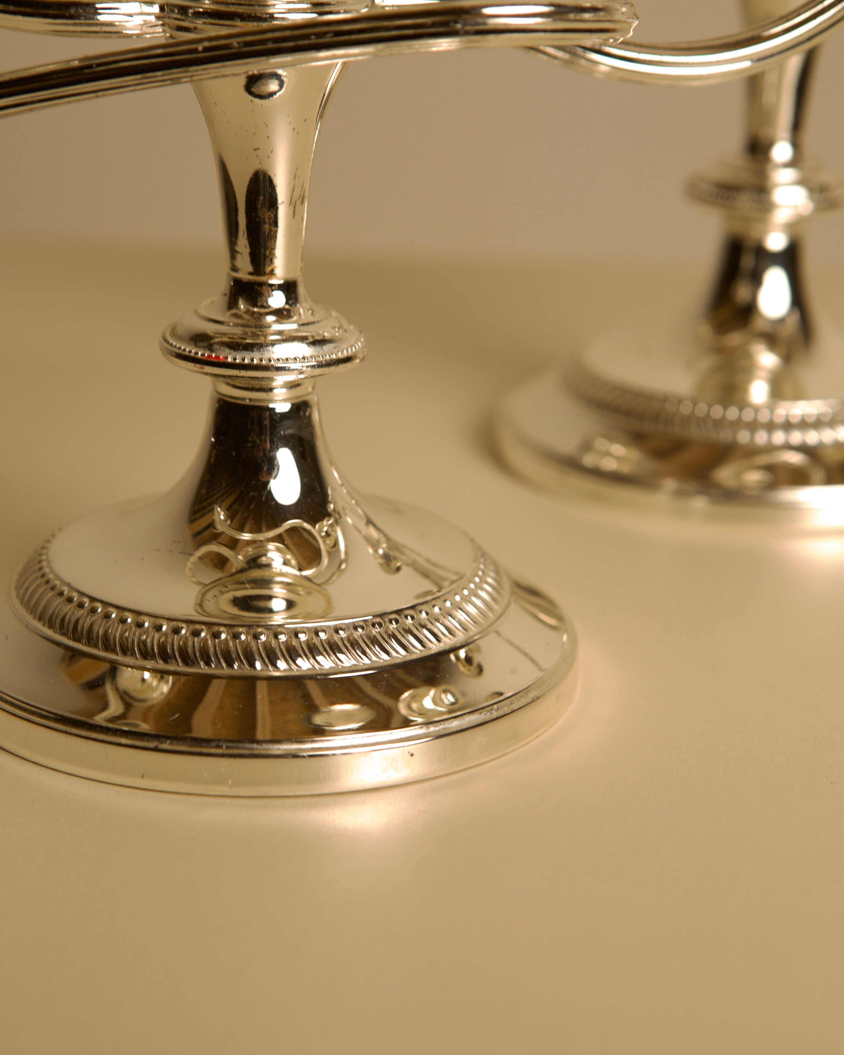 Pair of Italian metal "Medusa" candlesticks, 1980s — close-up of polished silver bases