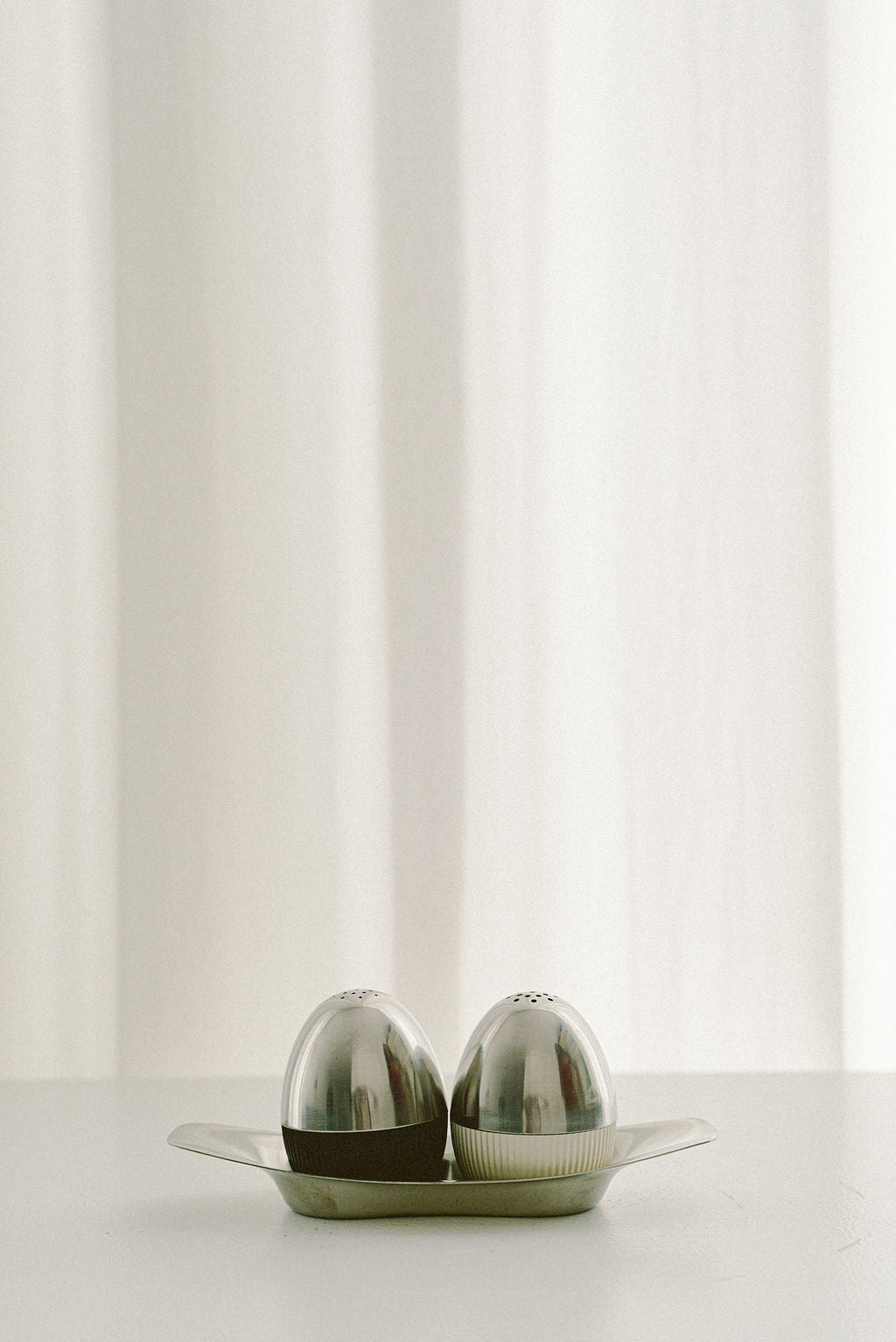 WMF Salt & Pepper Set by Wilhelm Wagenfeld — close-up of polished stainless steel on white table
