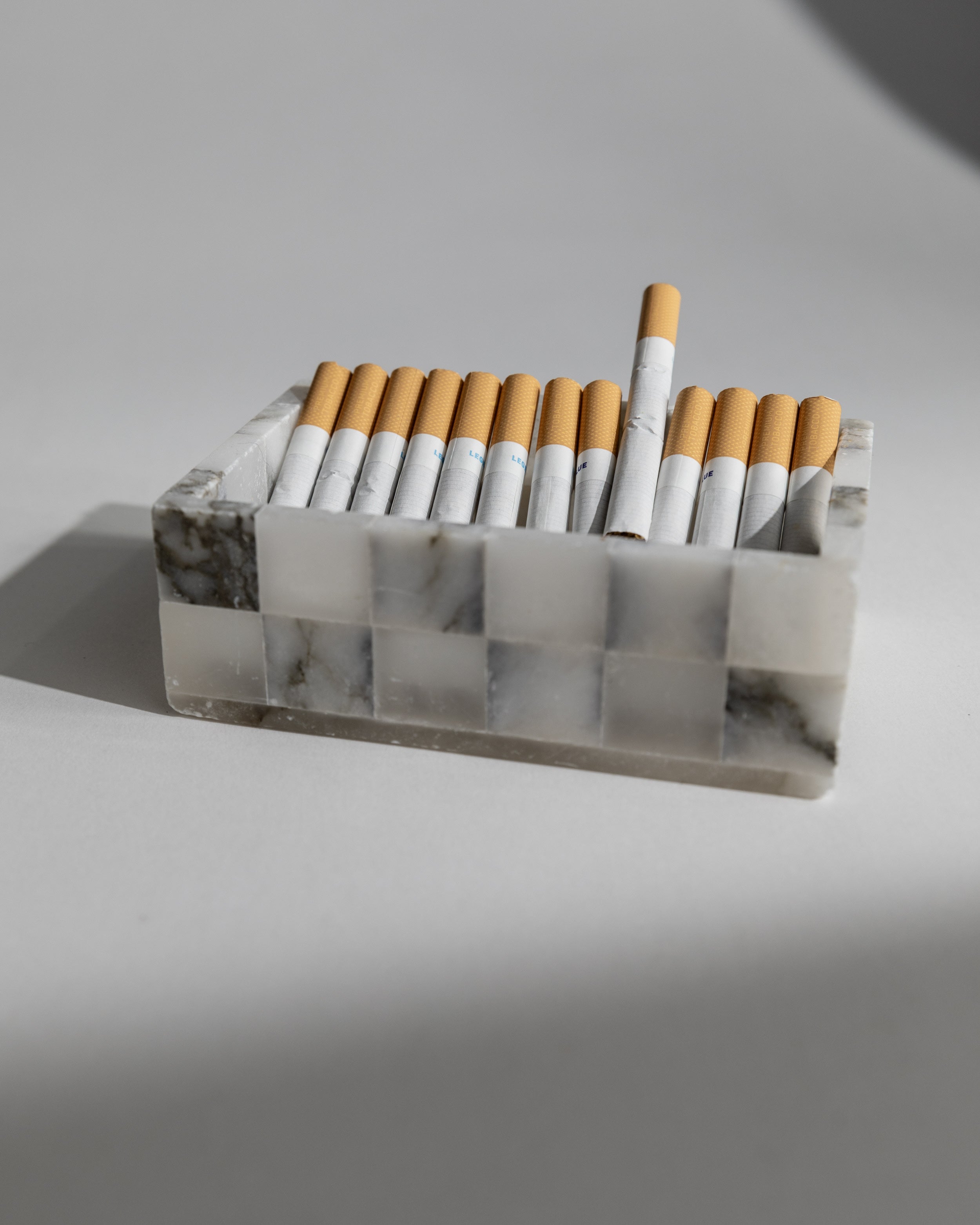 White marble cigarette holder with orange filter cigarettes detail