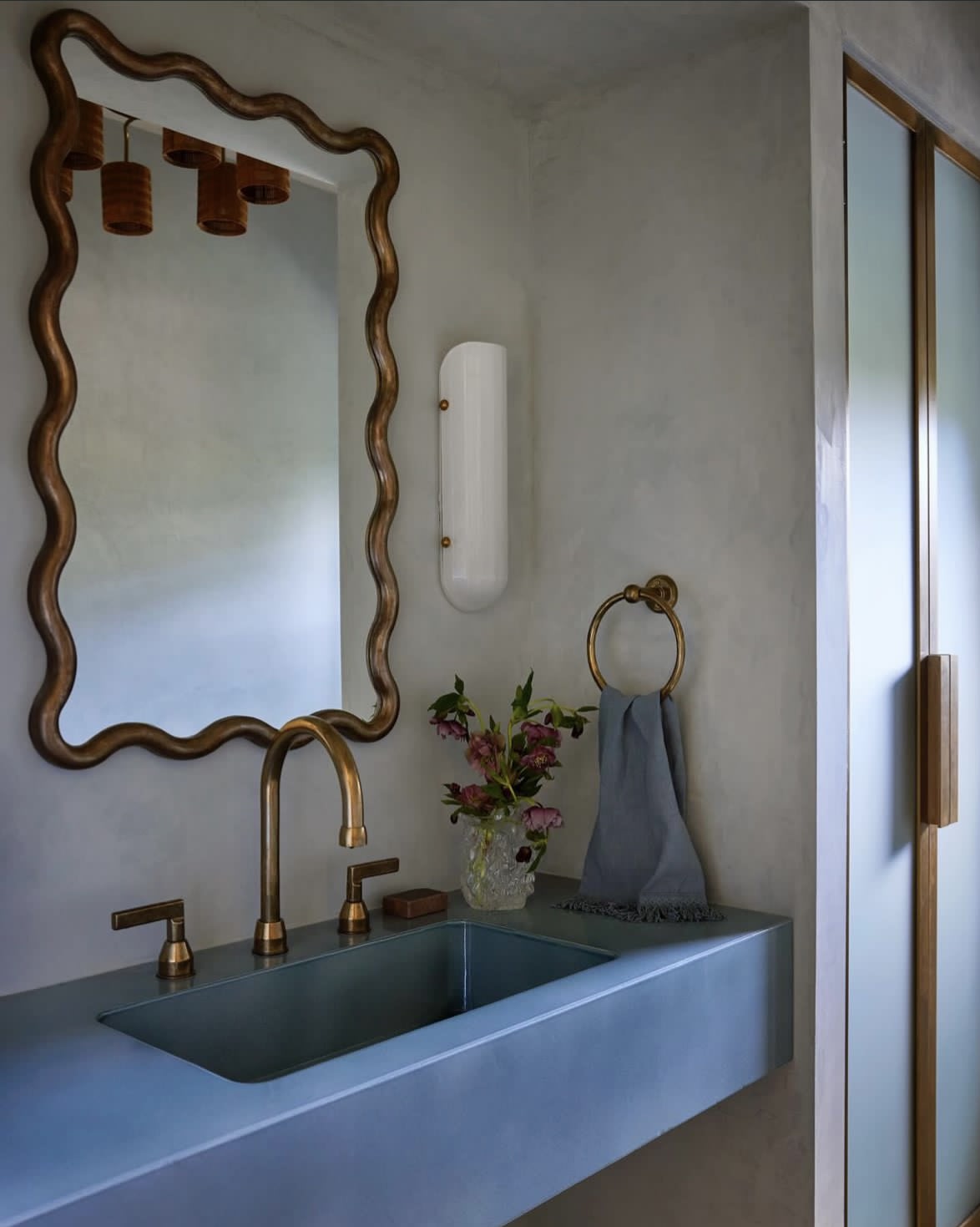 Selene Blown Glass Quartz Wall LED Wall Sconce with Brass Metal Hardware — installed above modern blue sink in bathroom