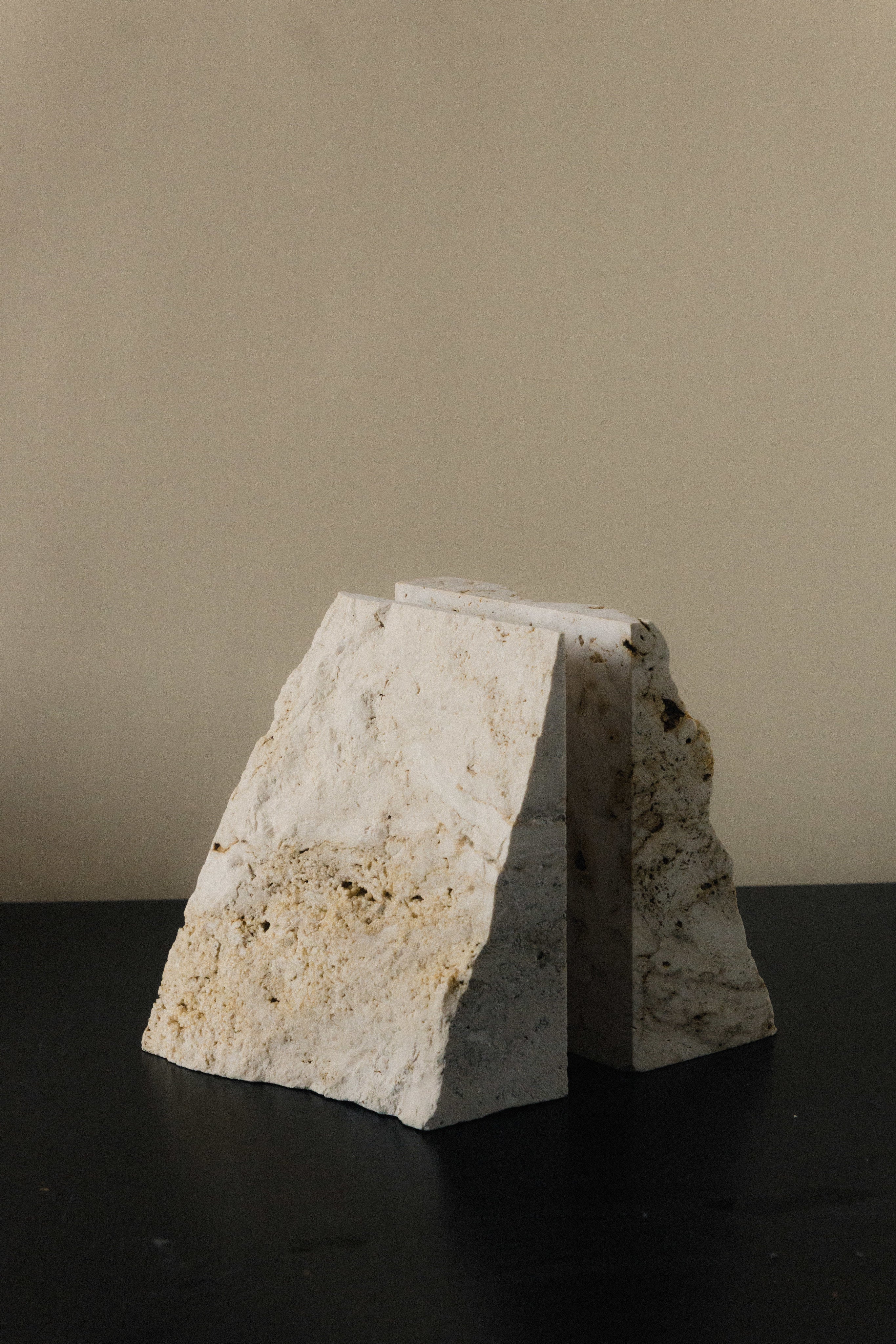 The Fragma Bookend III - Handmade Travertine Marble Bookend — side angle on black surface