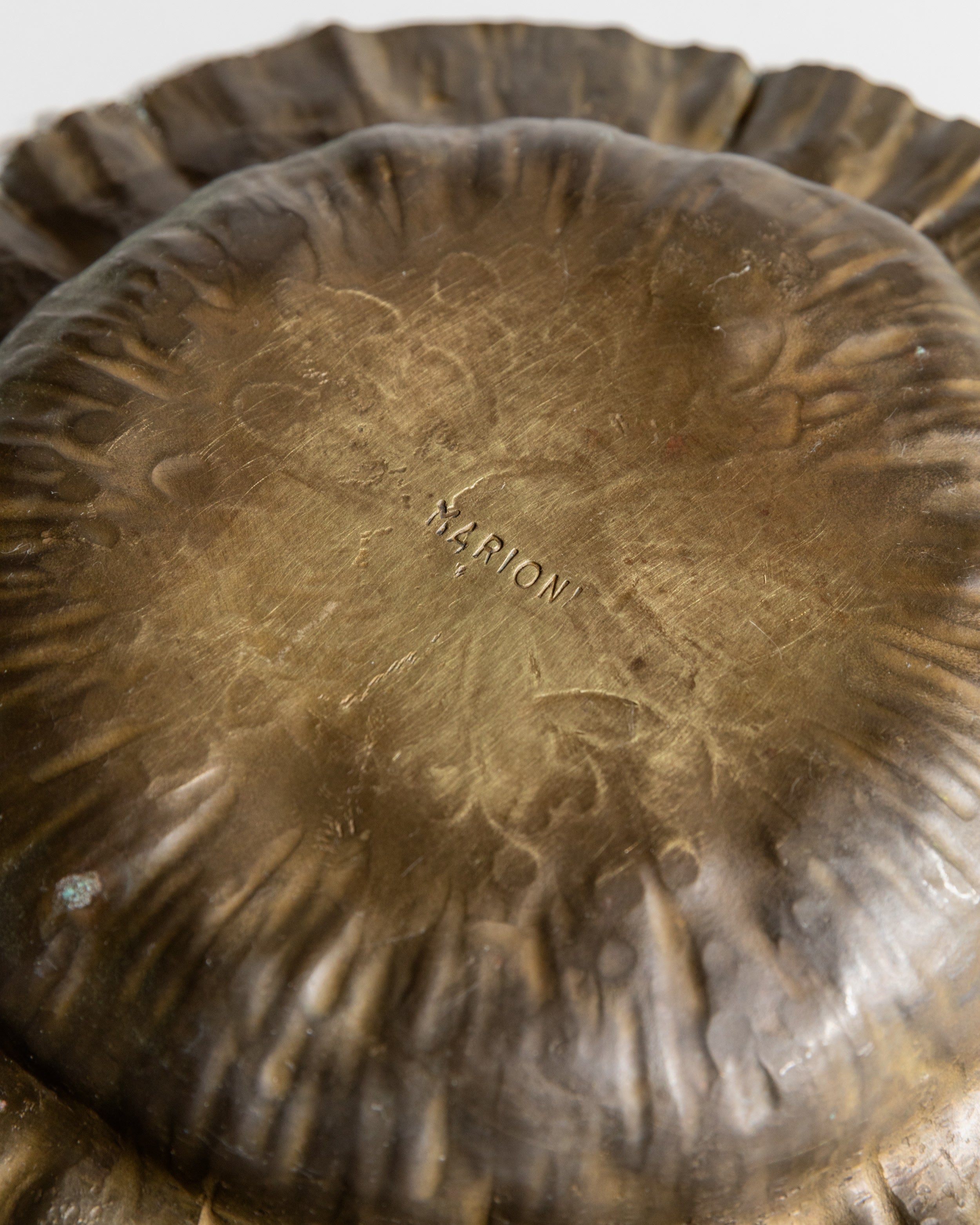 Close-up detail of brass bowl interior showing Marioni maker's mark