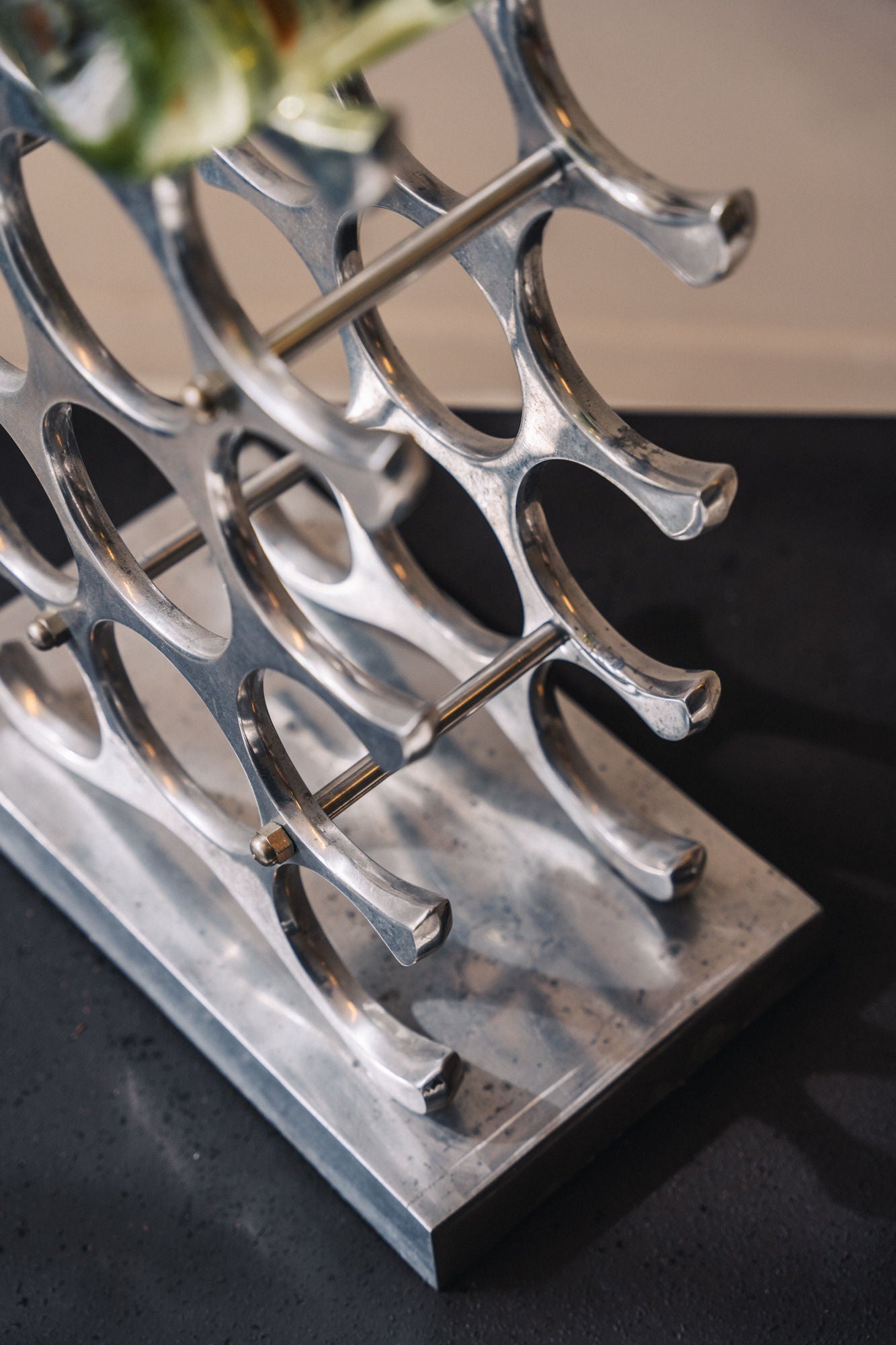 Modern chrome wine rack with curved slots on acrylic base