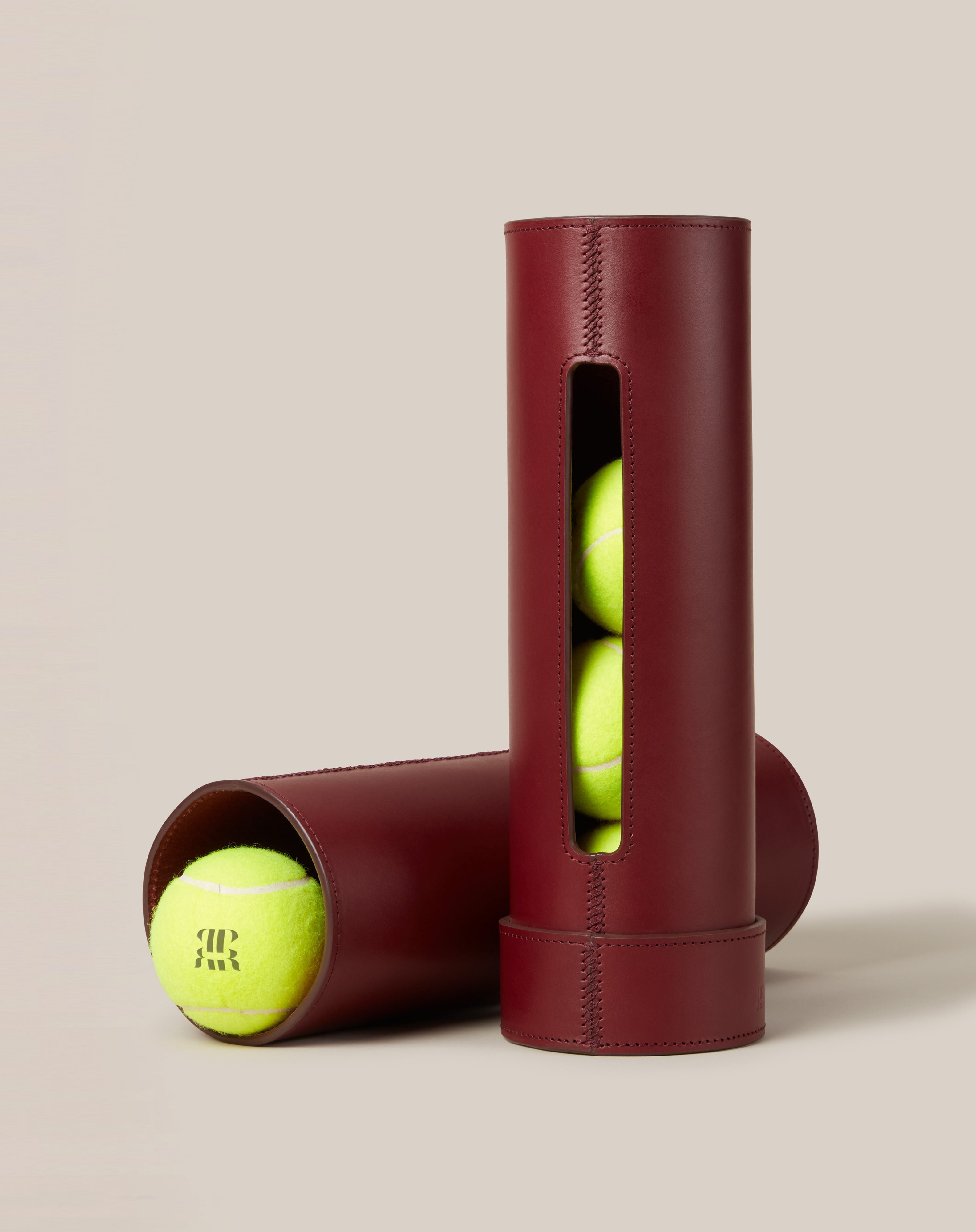 Leather Tennis Ball Holder — side angle showing burgundy leather with tennis balls inside