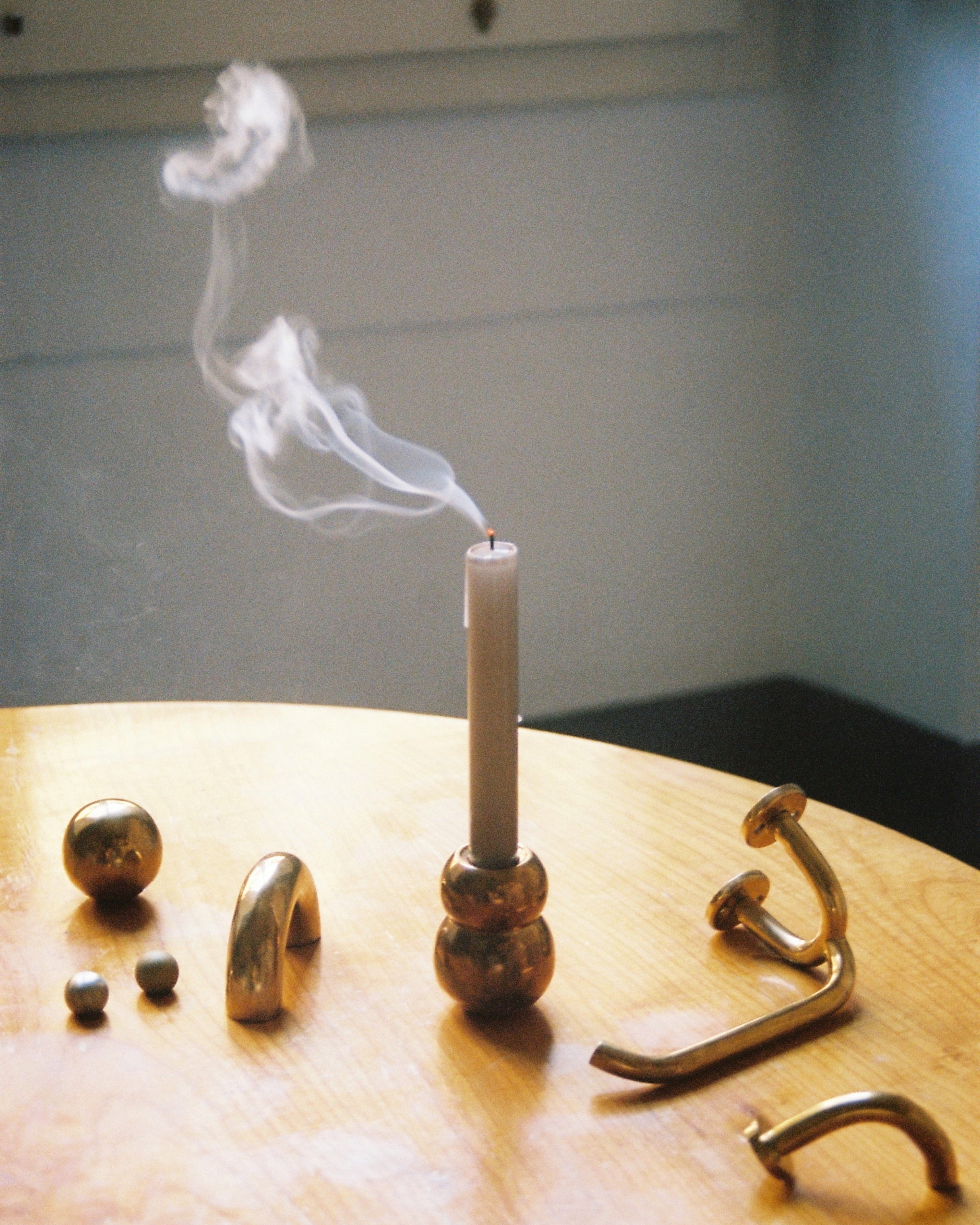 ANJOU Candleholder — smoke rising from brass candleholder on wooden table