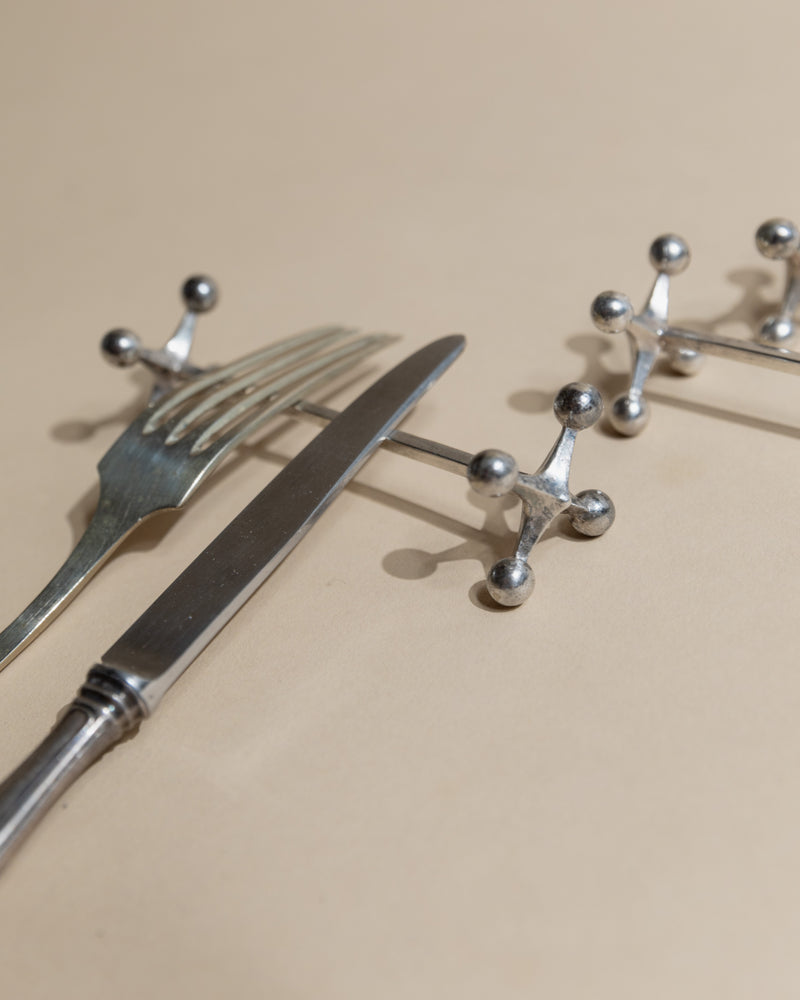 Close-up detail of silver cutlery rests with ball-tipped supports