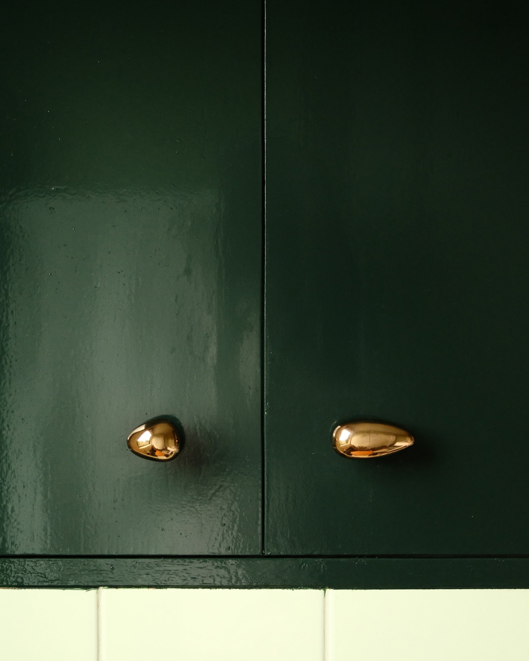 MOMI Cabinet Knob/Wall Hook Long Mini — close-up of shiny brass knobs on green cabinet