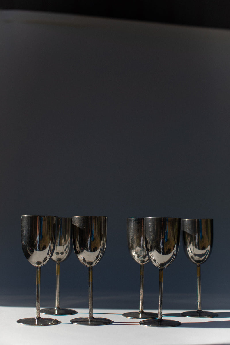 Set of 6 elegant brass champagne flutes on white surface