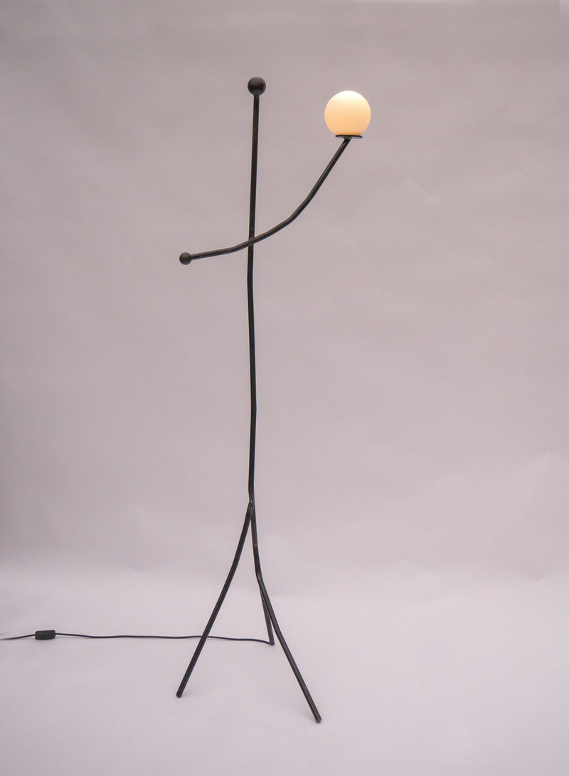 Modern black metal floor lamp with glowing spherical shade and tripod base