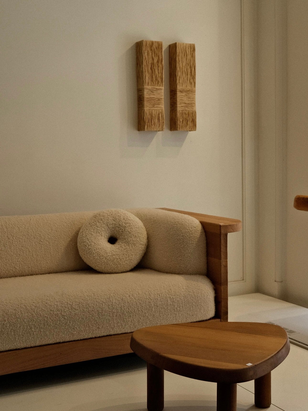 Eliane Wall Sconce in raffia — installed above a textured sofa