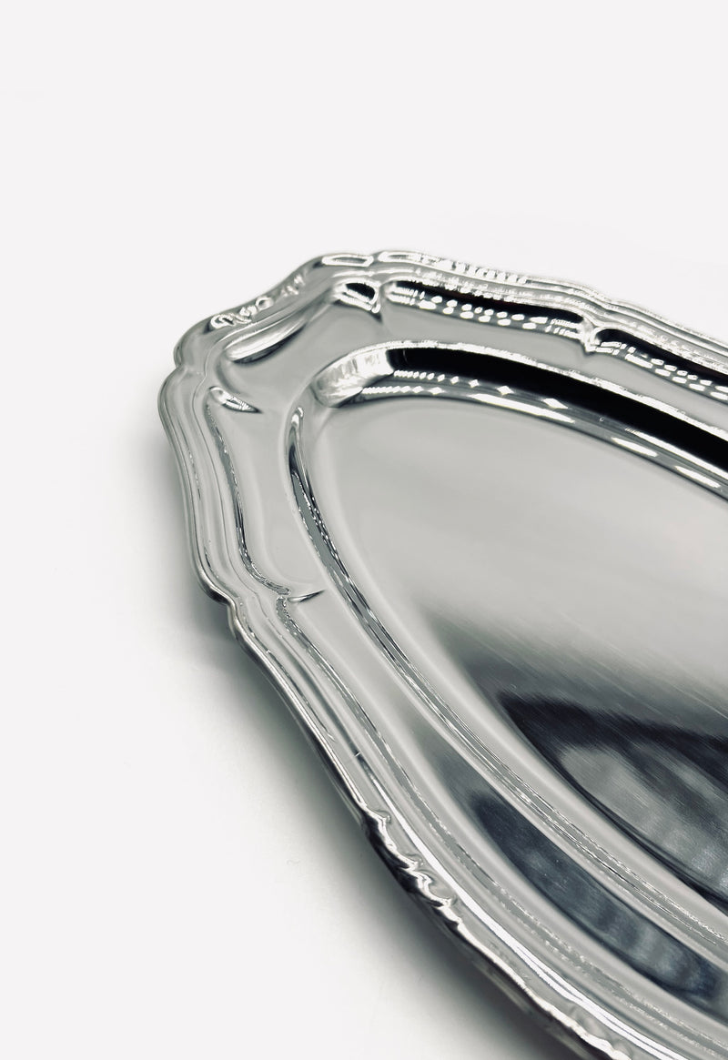 Corner detail of vintage stainless steel serving dish with ornate border