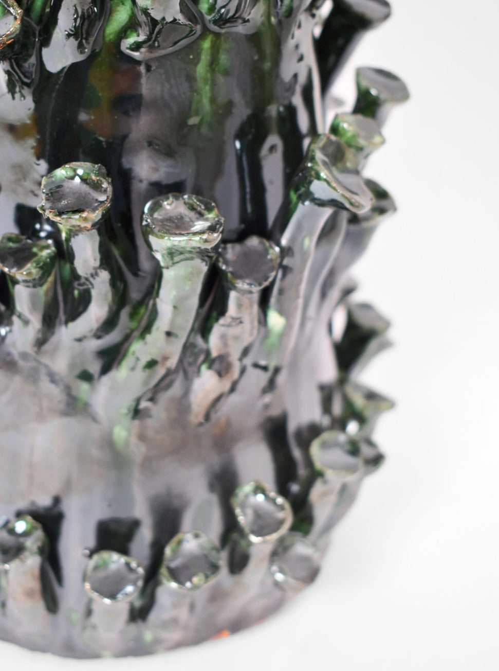 Close-up of the "Belize" Green and Black Lamp by Barracuda Interiors, featuring glossy dark green tubular shapes on a textured surface, evoking organic or underwater forms, shown against a plain white background.
