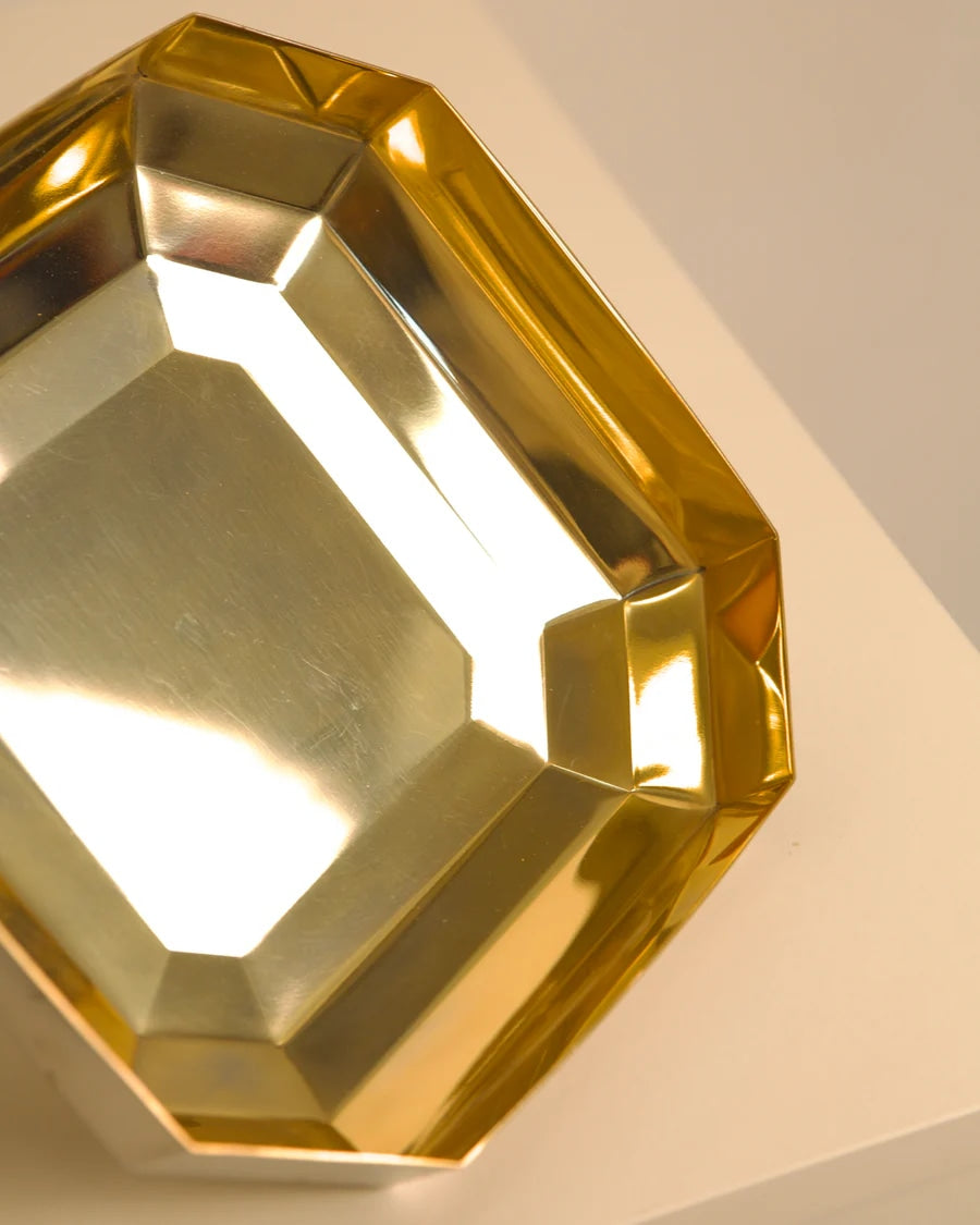 Golden metal vide-poche octagonal tray casting dramatic shadows