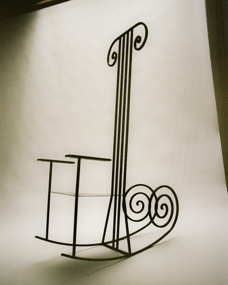 Minimalist wire rocking chair with elongated curved back design