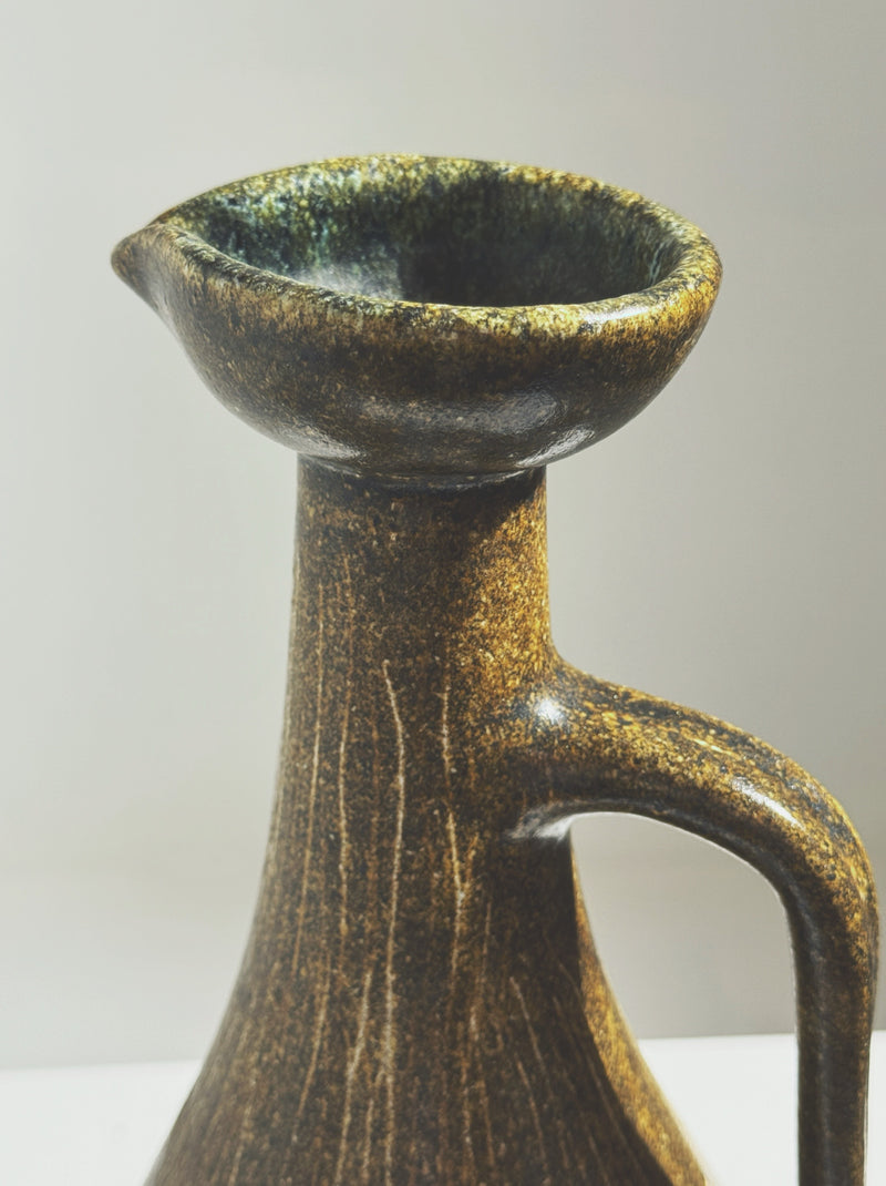 Close-up detail of Accolay ceramic pitcher with golden glaze finish