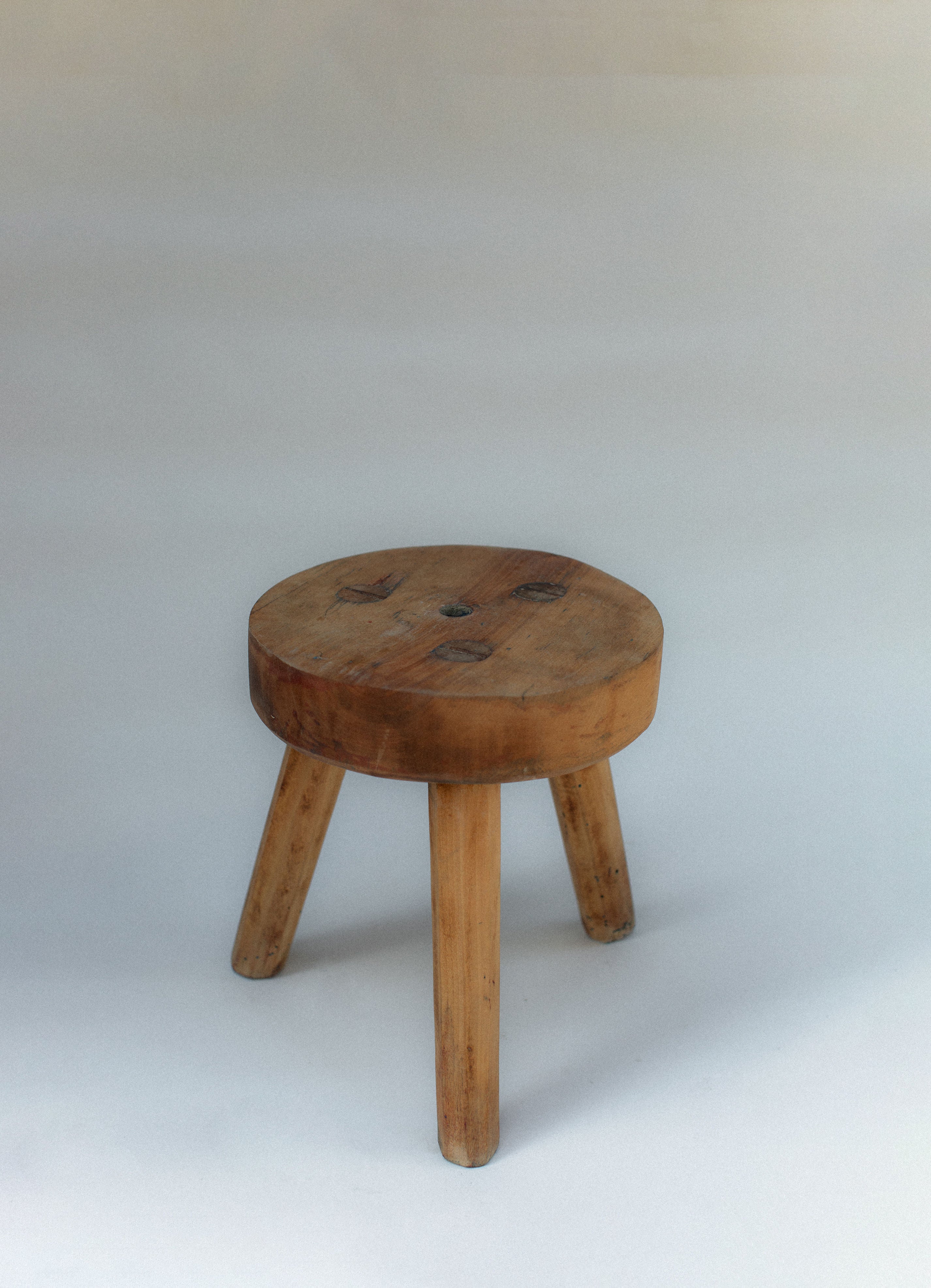 Rustic pine wooden stool with three legs and natural wood grain