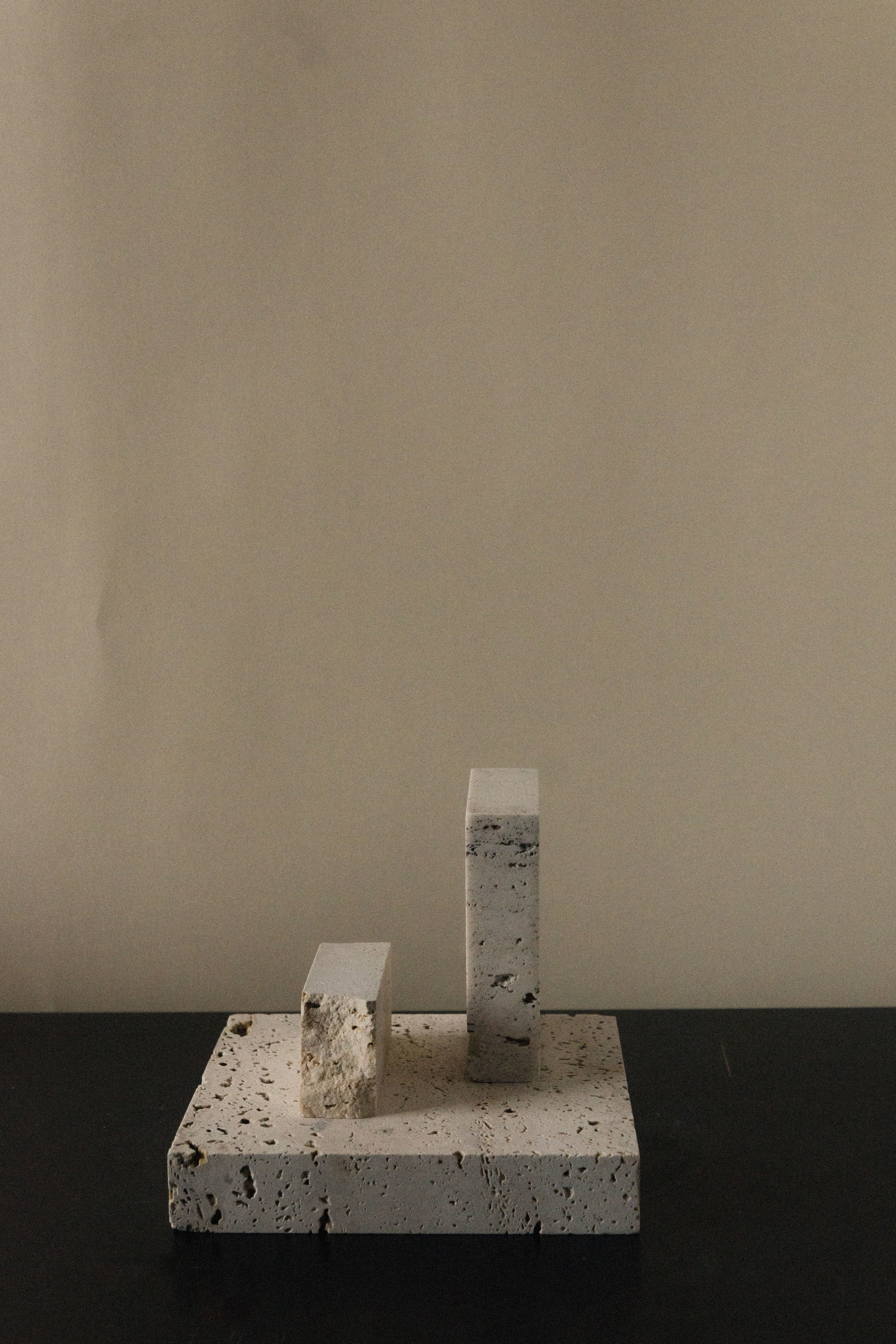 Monument II - Handmade Travertine Marble Bookstand — angled view on dark surface