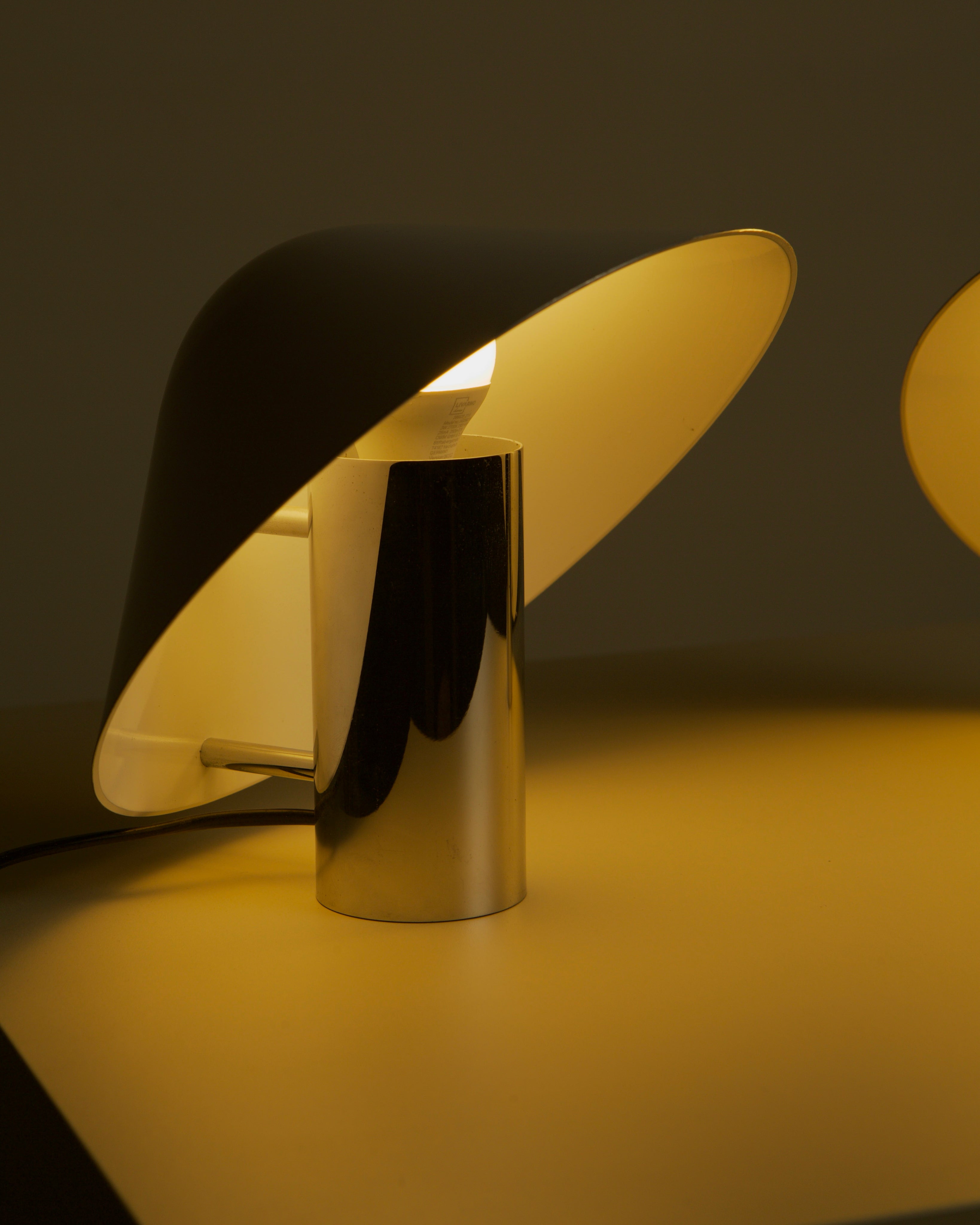 Illuminated Pulcino table lamp detail showing curved yellow shade and cylindrical base