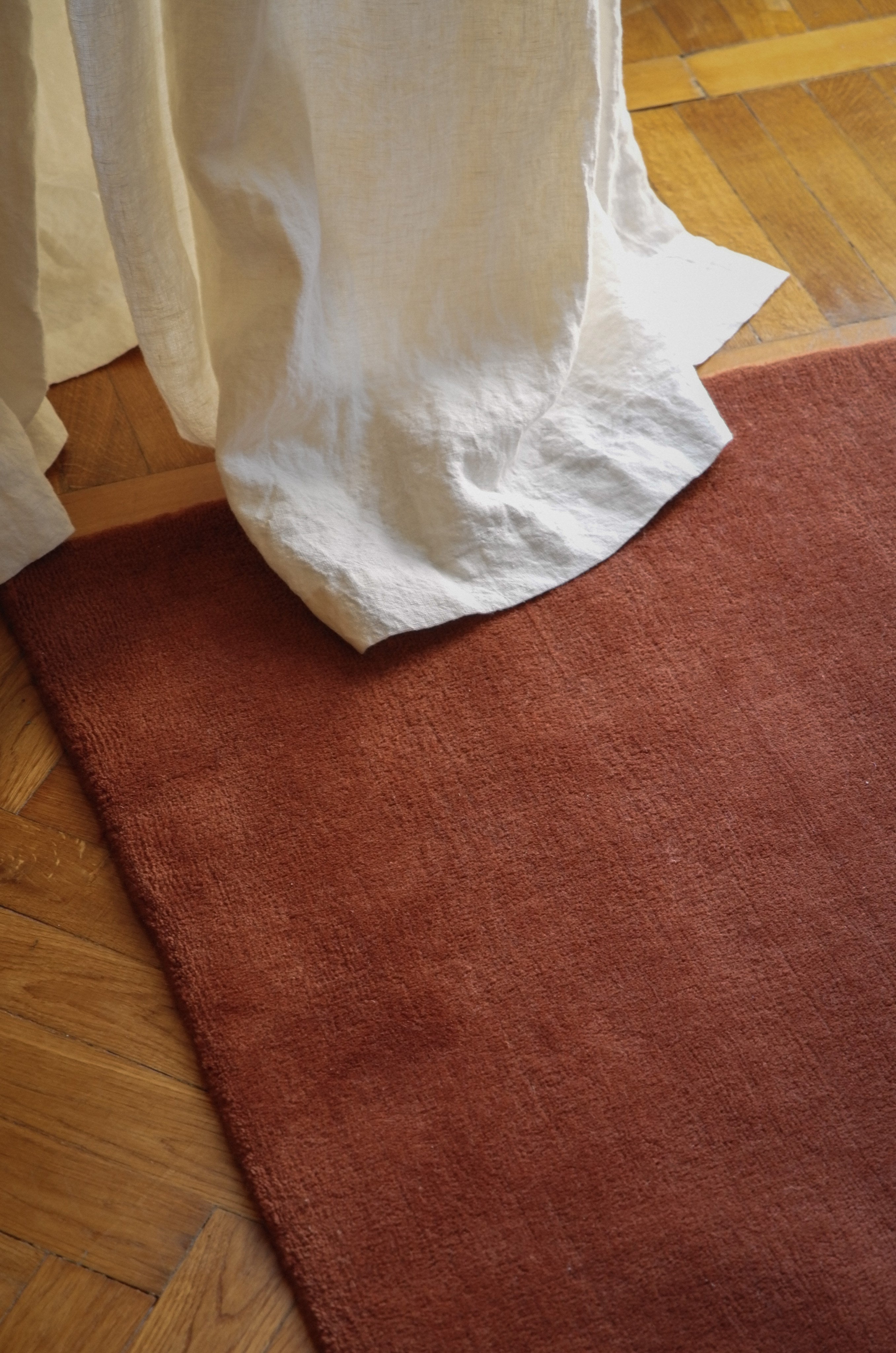 Hand-woven Rug in New Zealand Wool, Rouille — corner view on hardwood floor