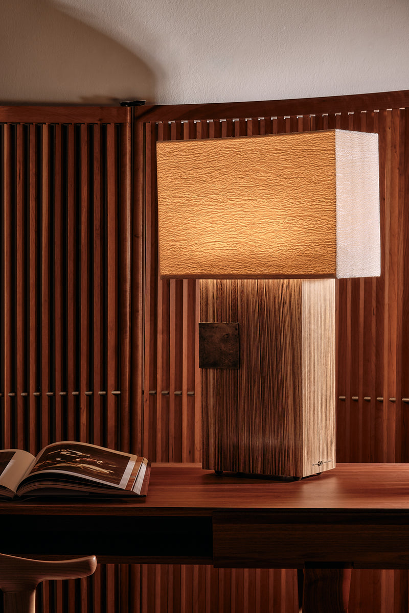 Pollux table lamp with textured shade on wood-paneled desk