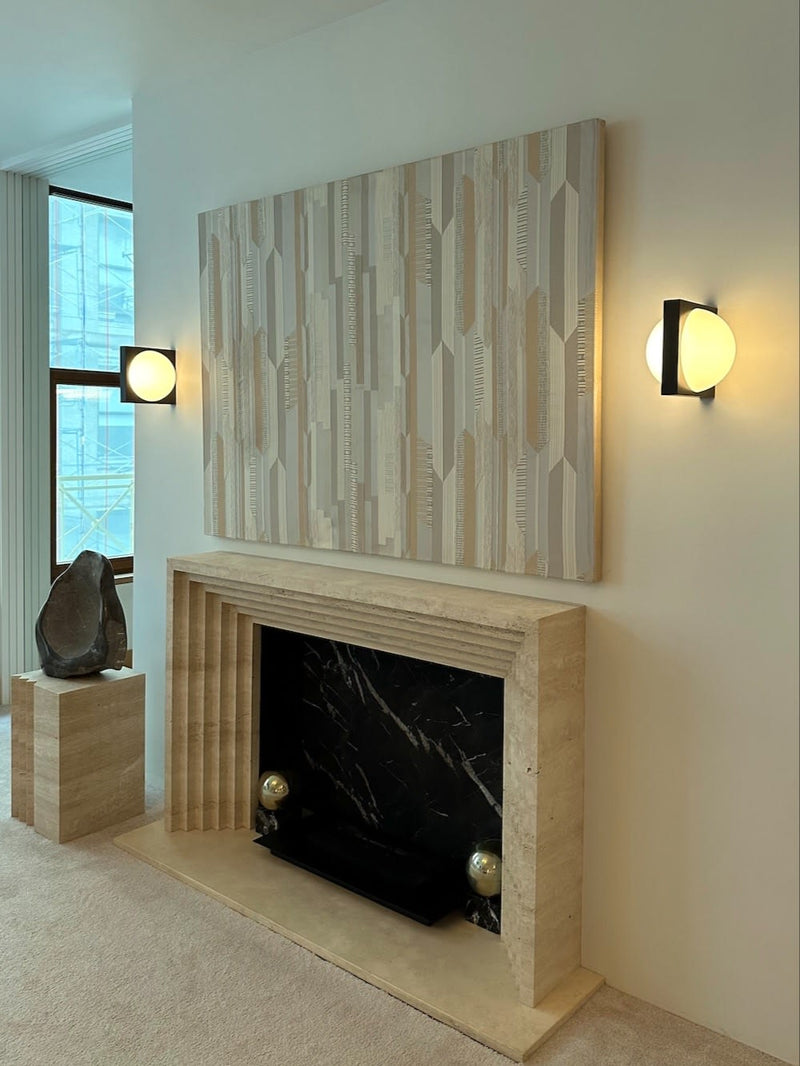 Solstice Wall Light — installed on wall beside modern fireplace