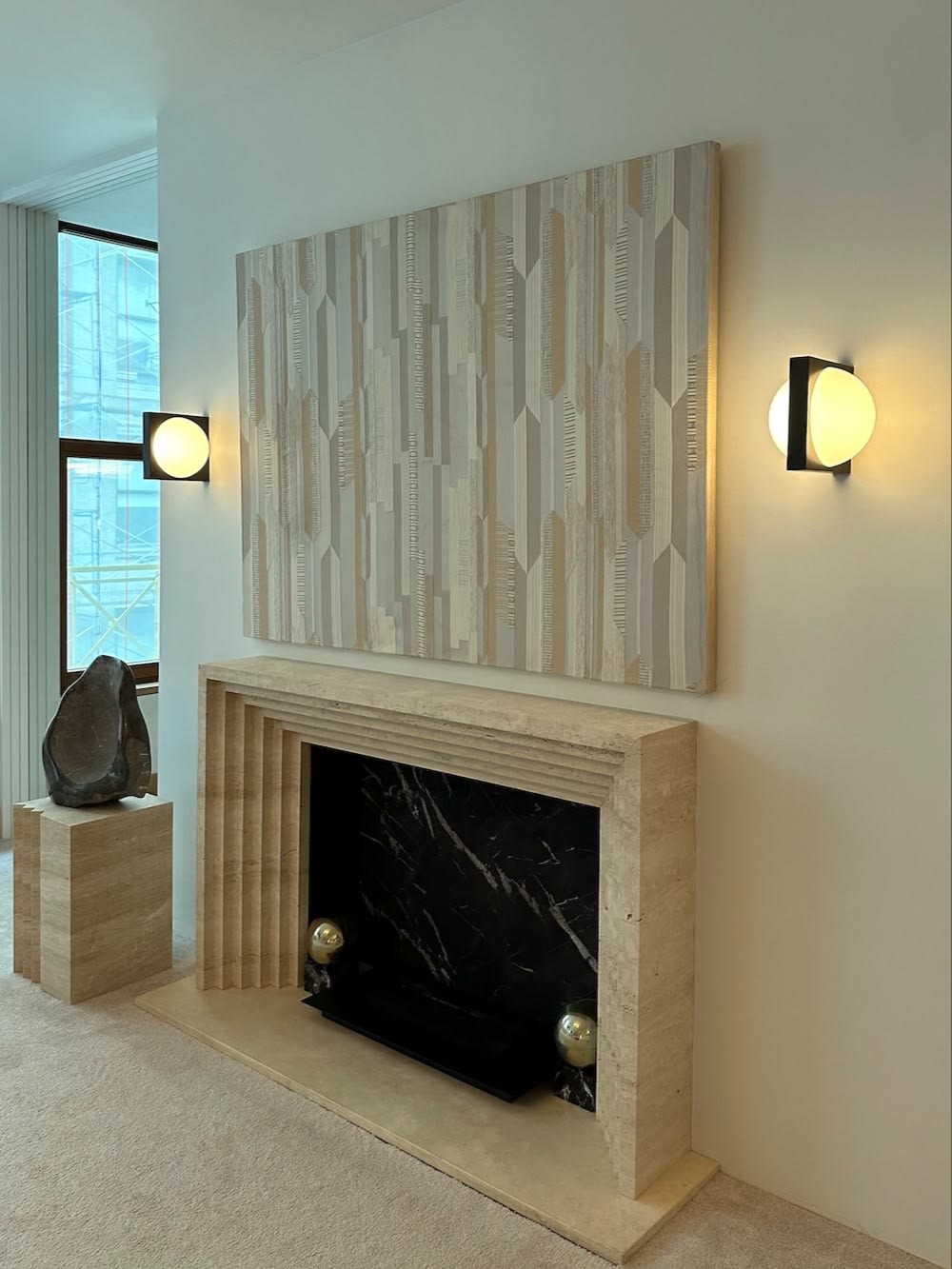 Solstice Wall Light — installed on wall beside modern fireplace