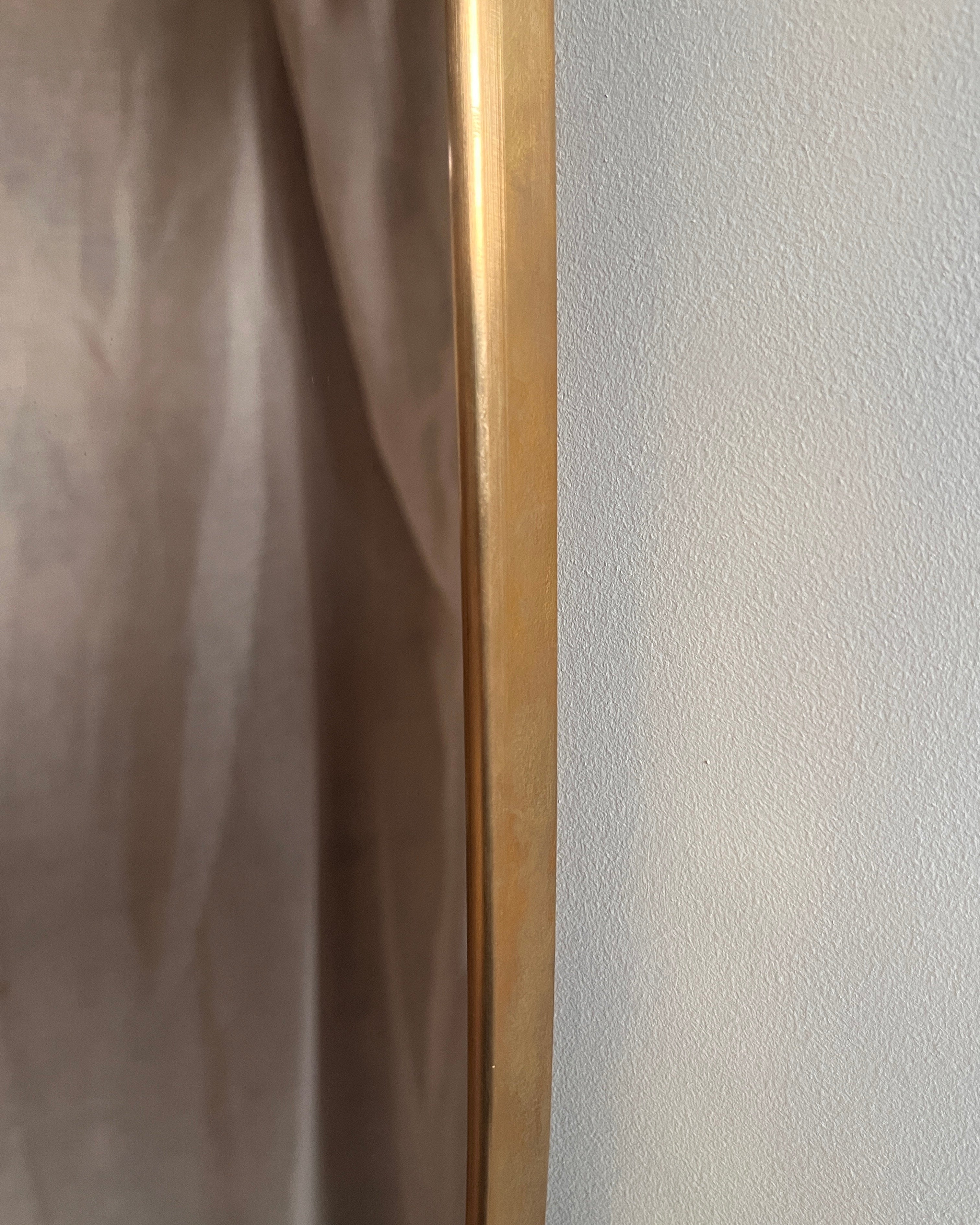 Close-up detail of brass frame edge and textured wall backdrop