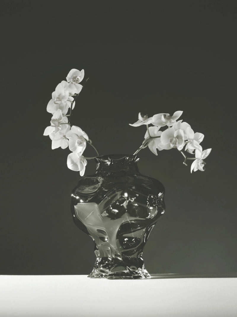 Ammonit Vase - New Smoke — close-up of glass vase with white flowers