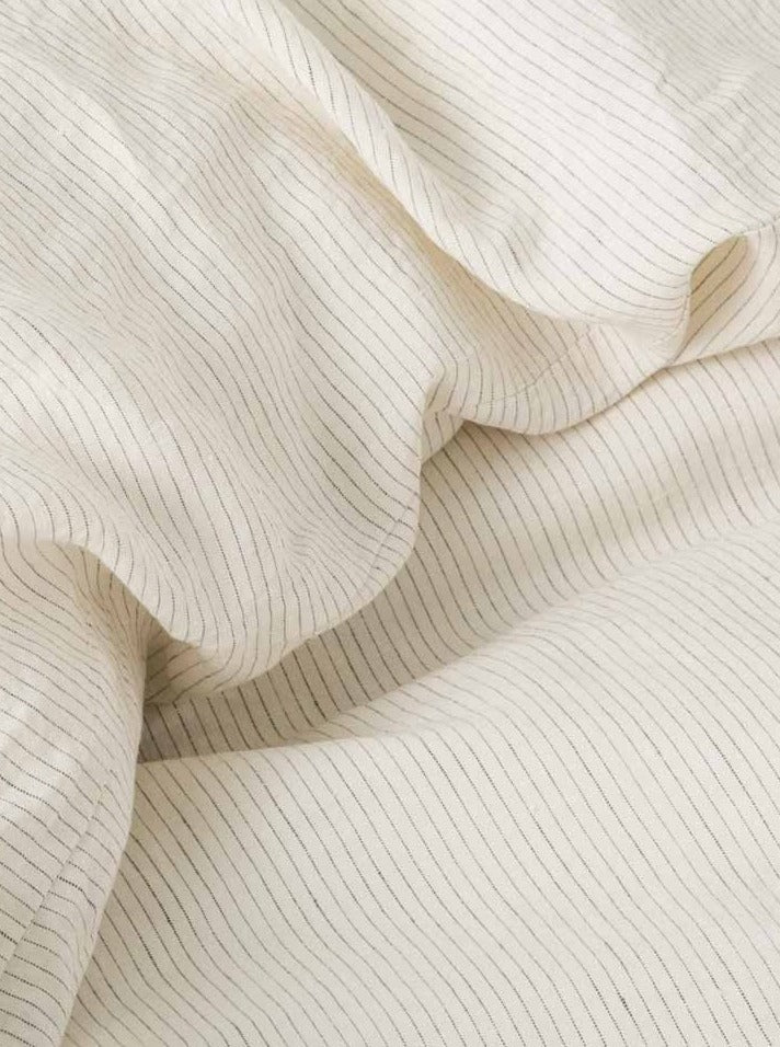 Close-up image of a MOST Washed Linen Bed Set in Stripes with delicate, evenly spaced lines creating a gentle wave pattern on a soft beige background.