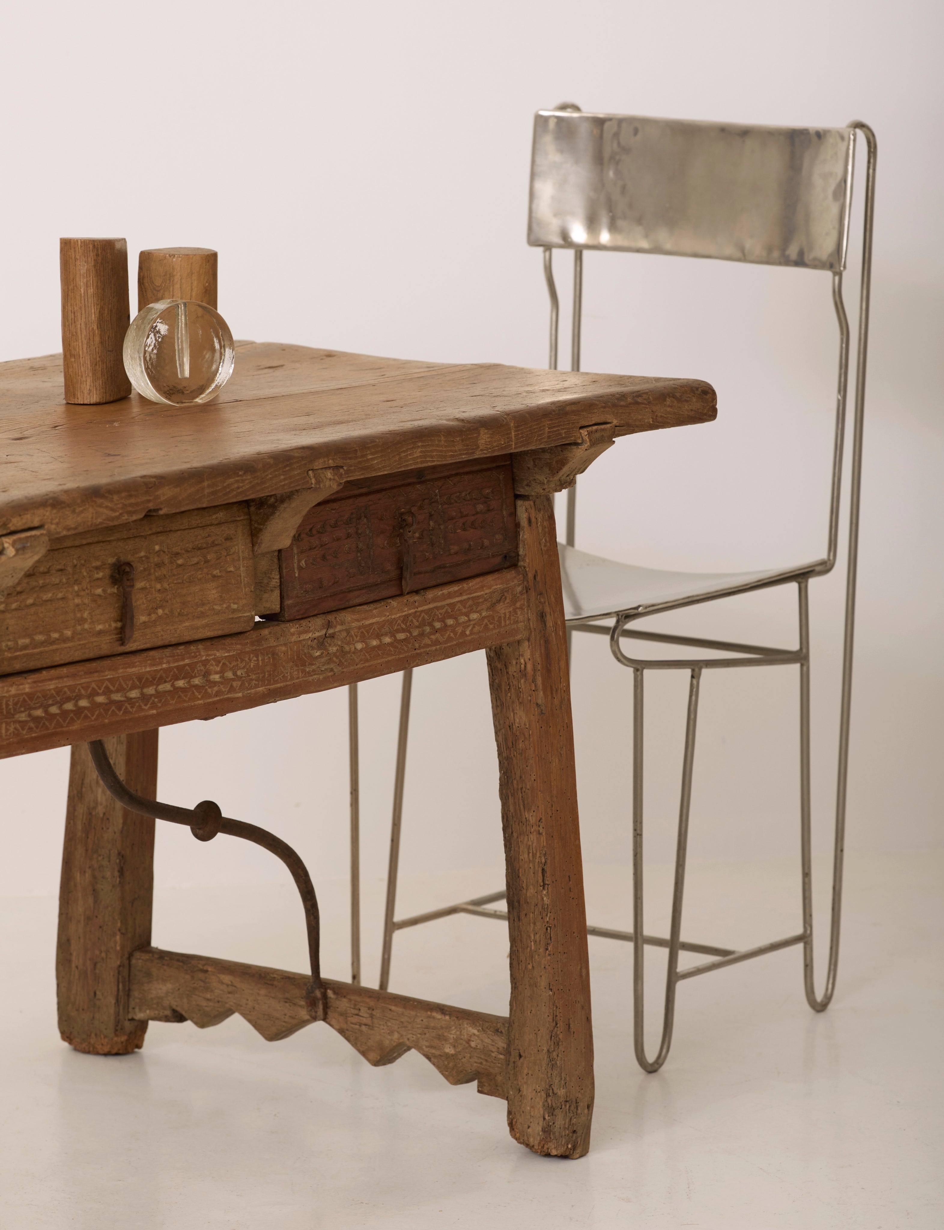 Spanish Folk Vernacular Table From The 17th Century — close-up of rustic wooden surface with metal chair