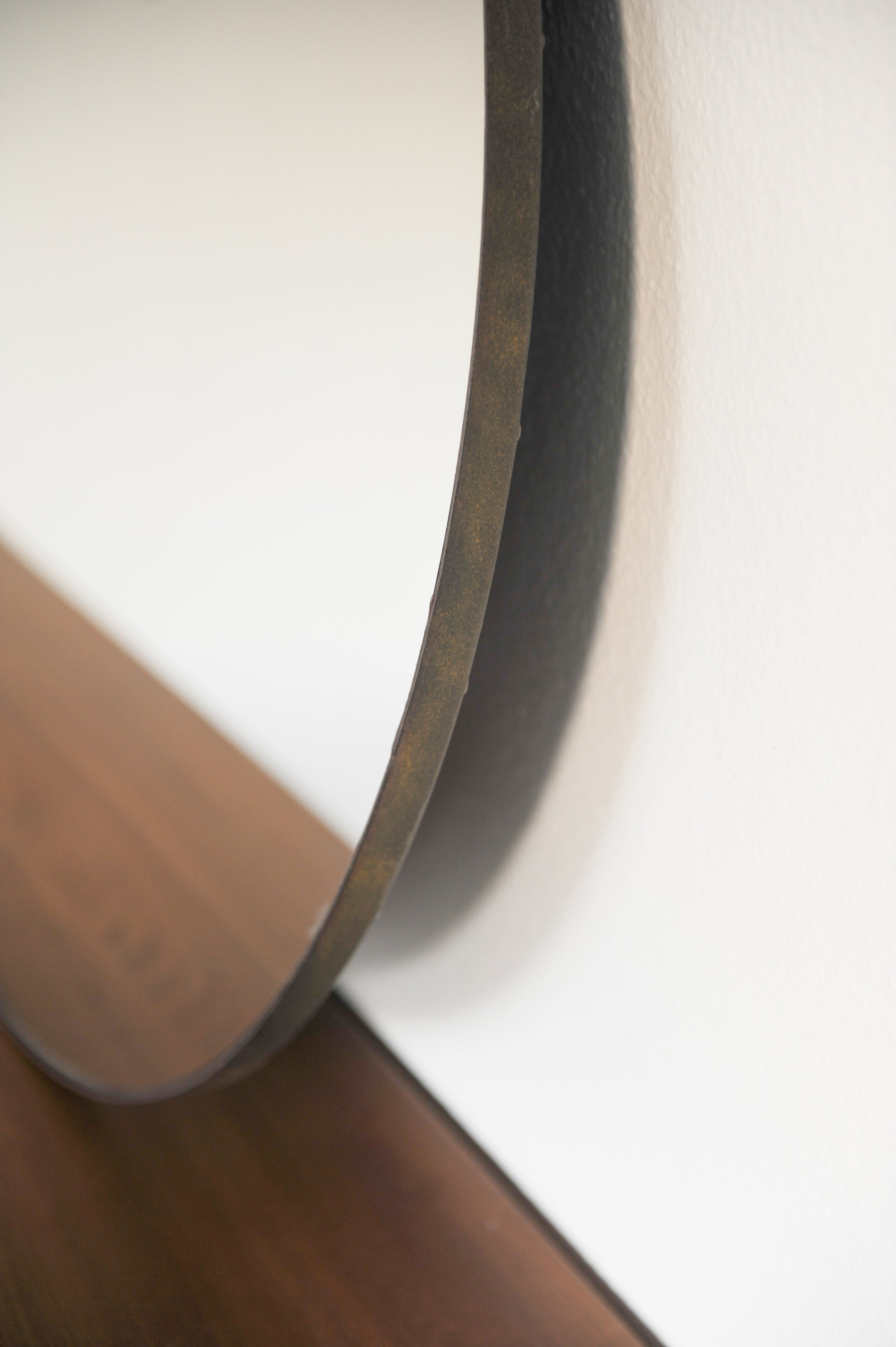 Close-up detail of circular mirror frame edge on wooden floor