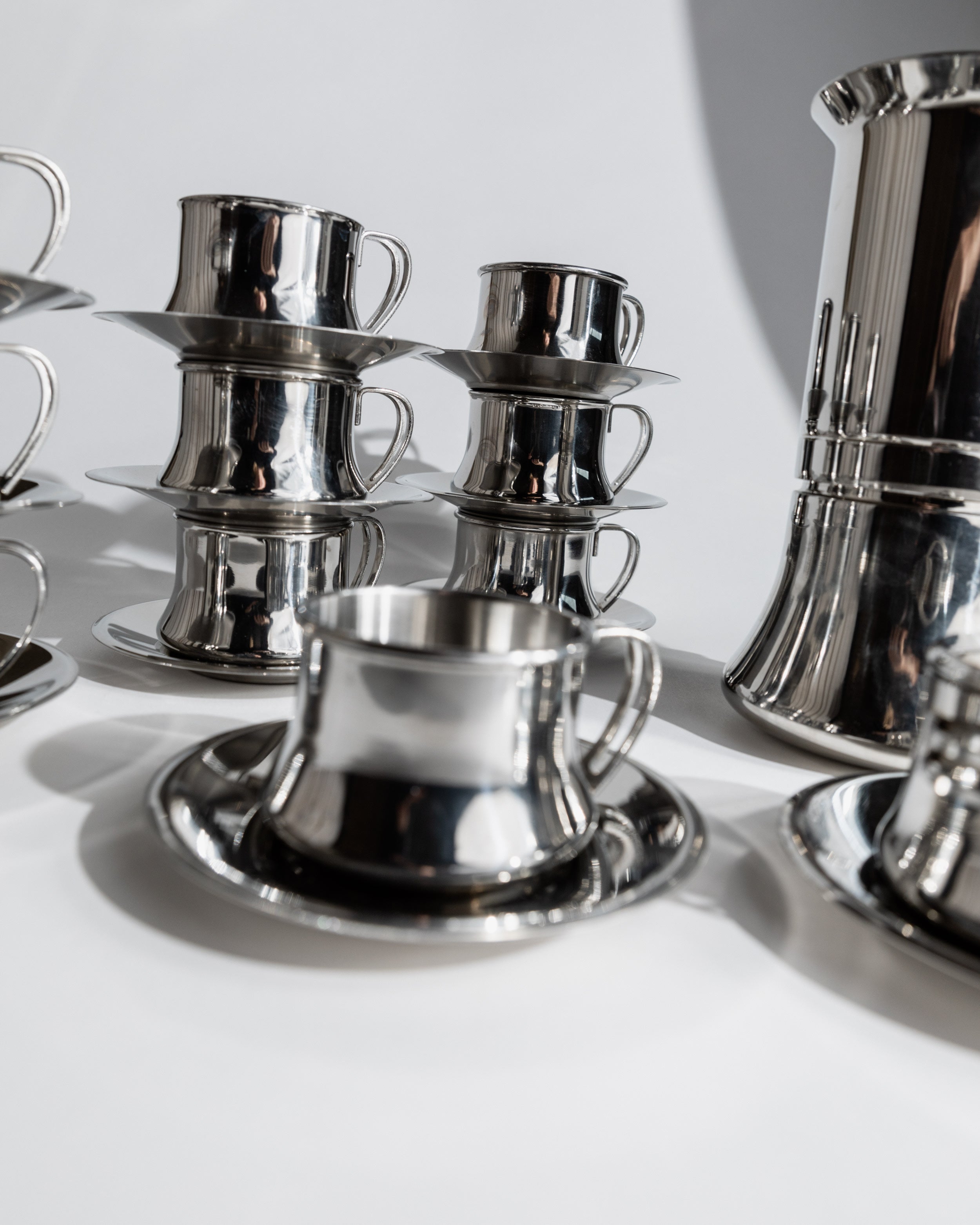 Stacked 1980s stainless steel coffee cups with saucers detail view