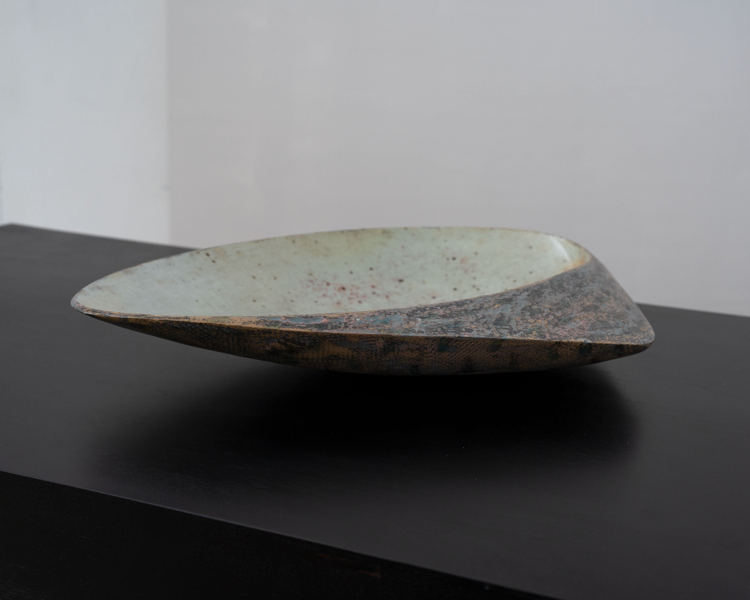 Large ceramic bowl profile view showing curved form and speckled glaze