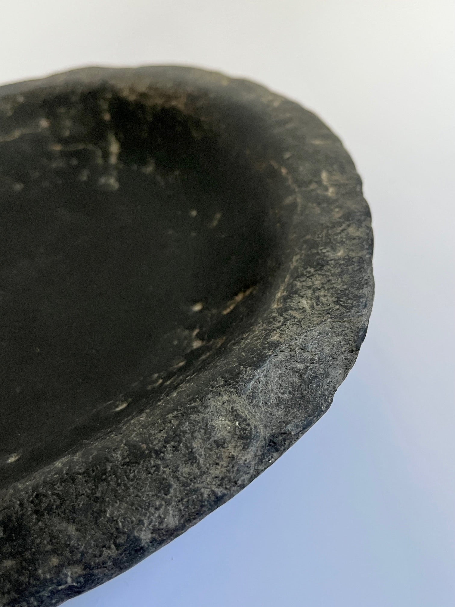 Close-up rim detail of antique black stone bowl showing weathered texture