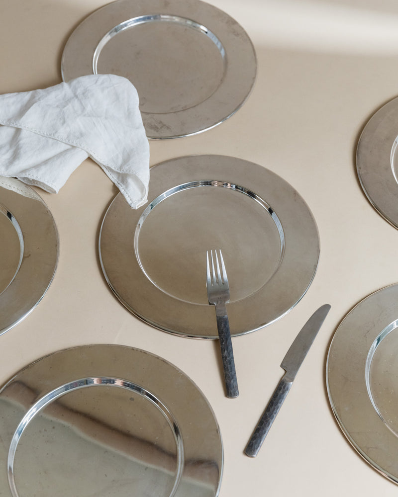 Silver-rimmed glass underplates arranged with vintage cutlery and napkin