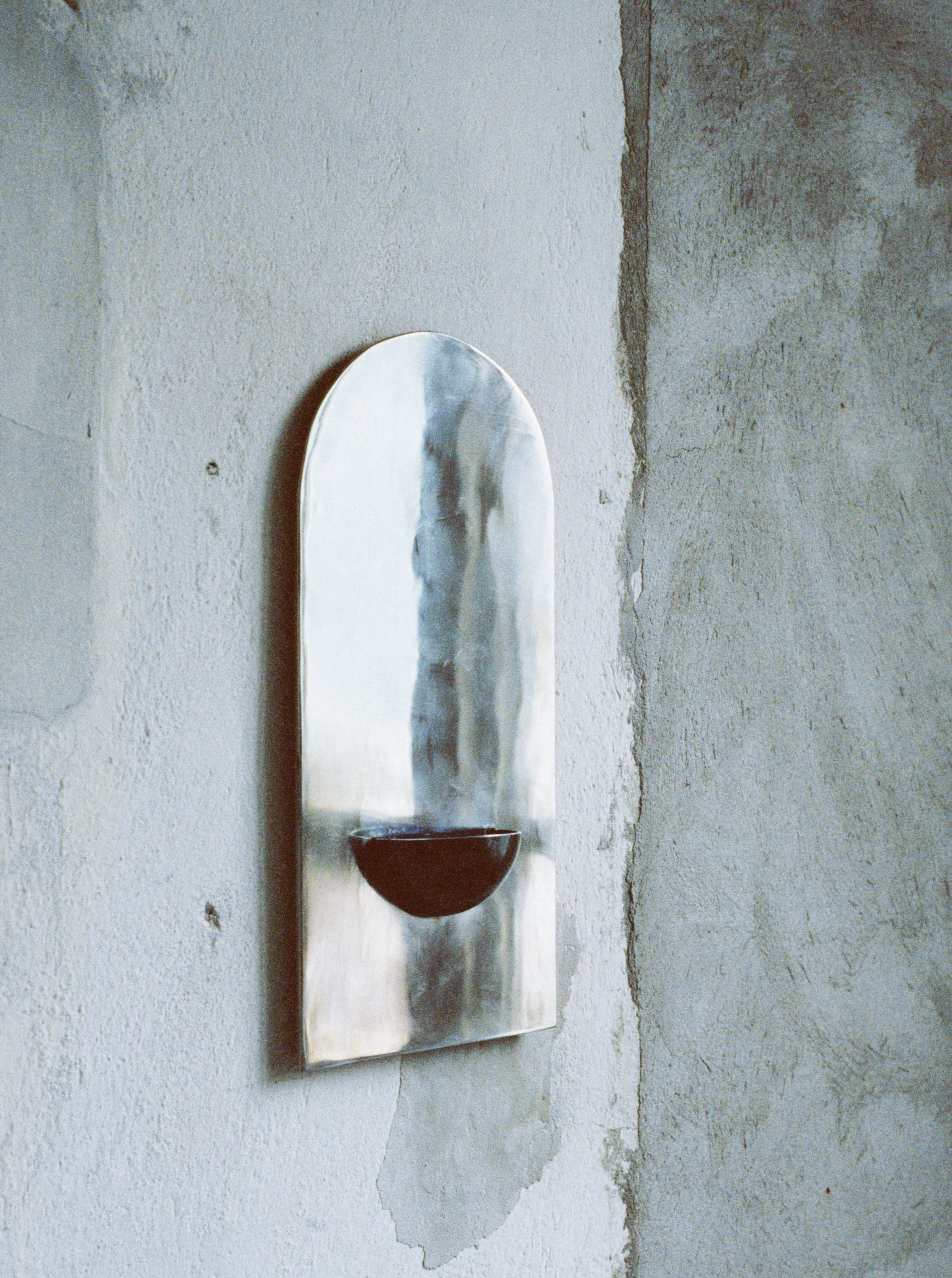 The Mirror of Simple Souls - Contemporary Mirror in Steel — side angle against textured wall