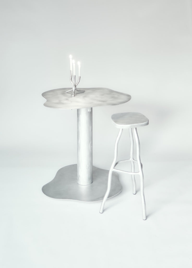 Bar Stool — close-up of silver metal seat beside table