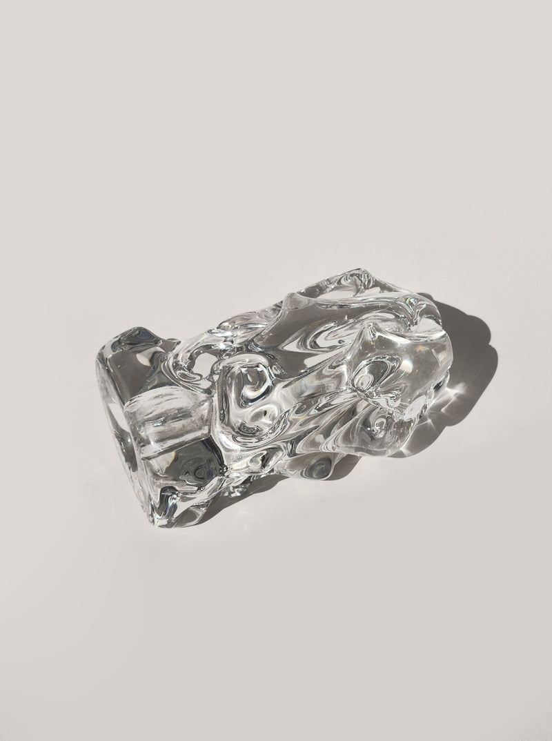 The Les Objoies Organic Glass Candle Holder features smooth, curved surfaces and a clear, abstract form that evokes biomorphic mid-century modern design, casting subtle shadows on a light, neutral background.