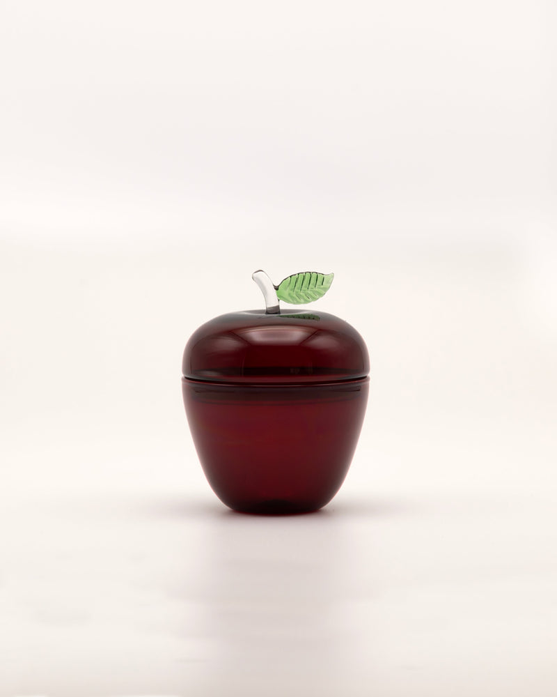 La Pomme — close-up of red glass apple container with green leaf