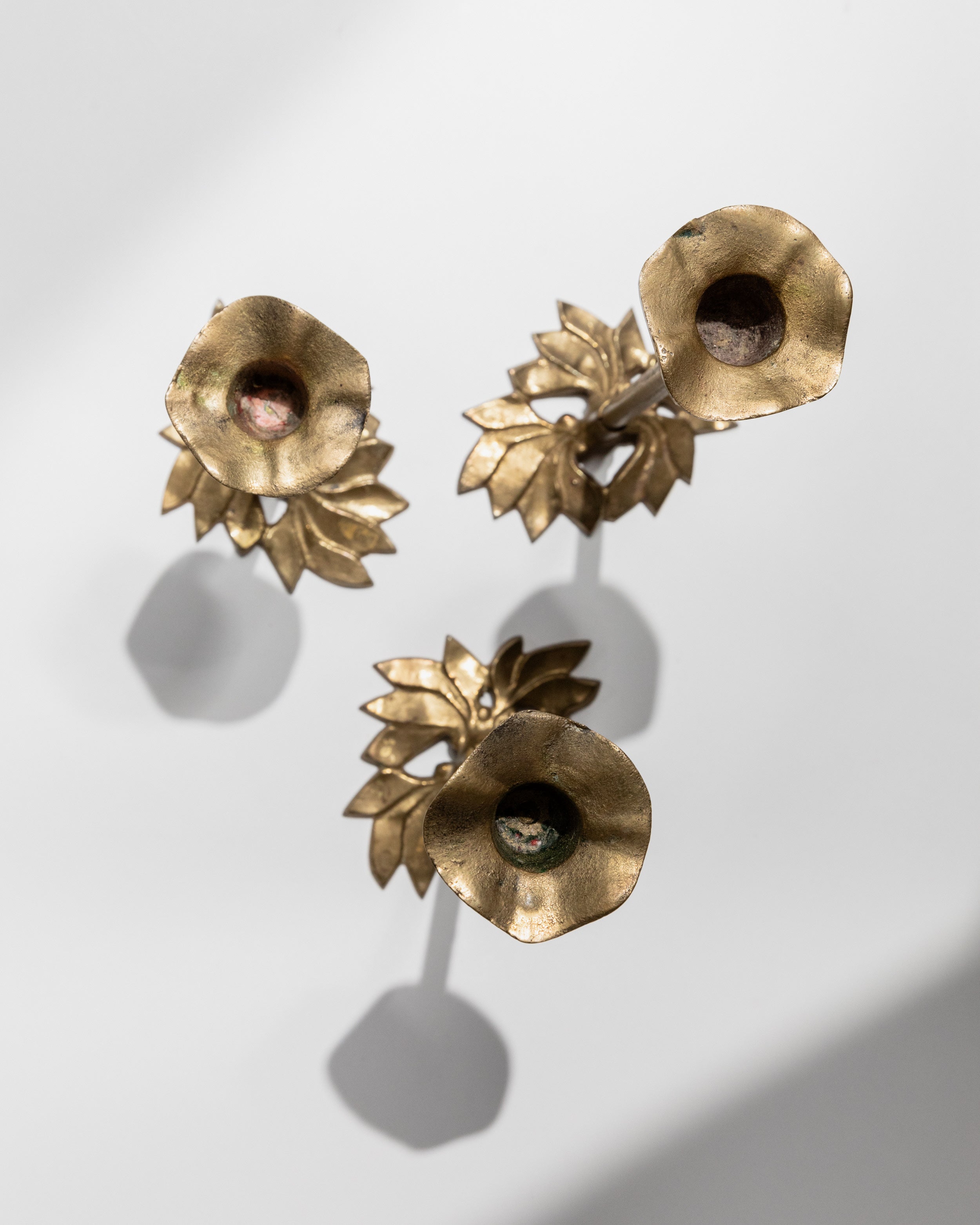 Brass candle holders with floral leaf bases from above view